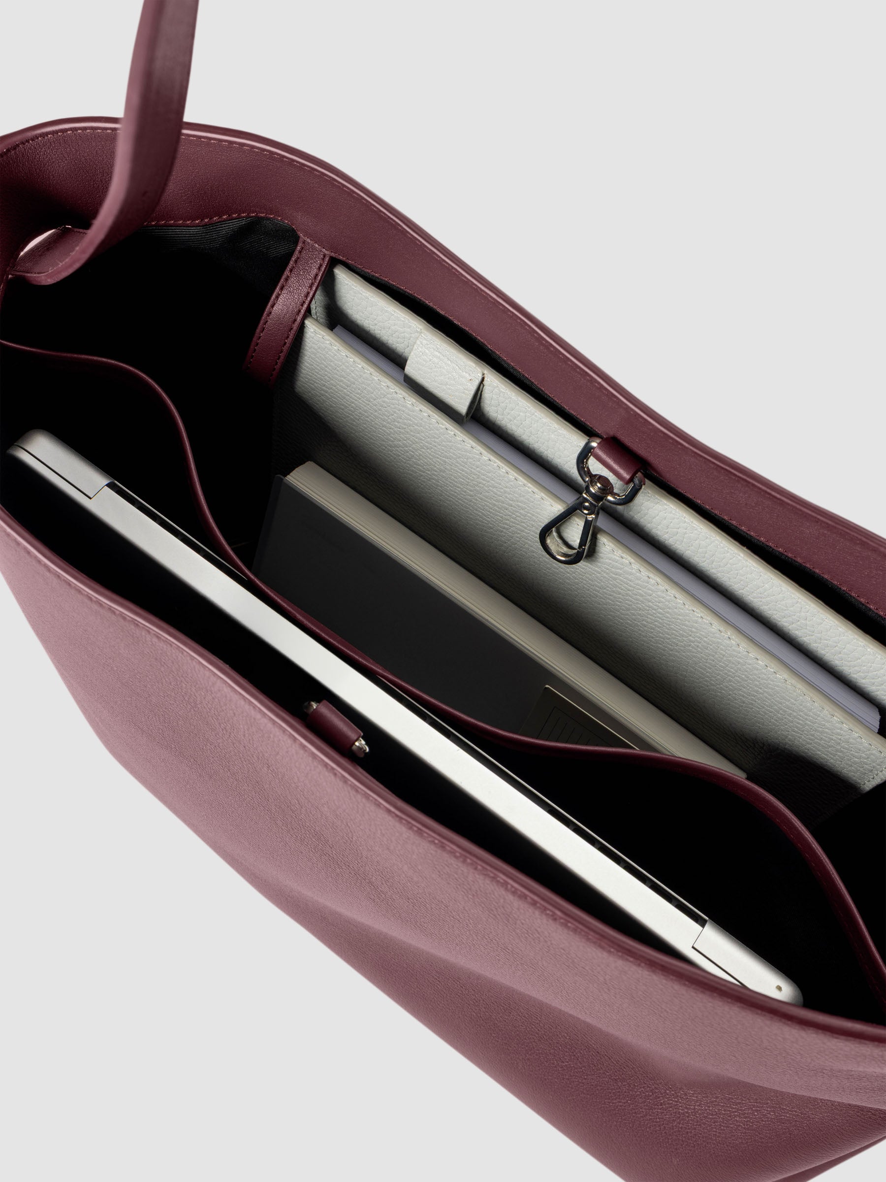 Detail view of a laptop and notebooks inside The Metro Tote in the color Madrid.