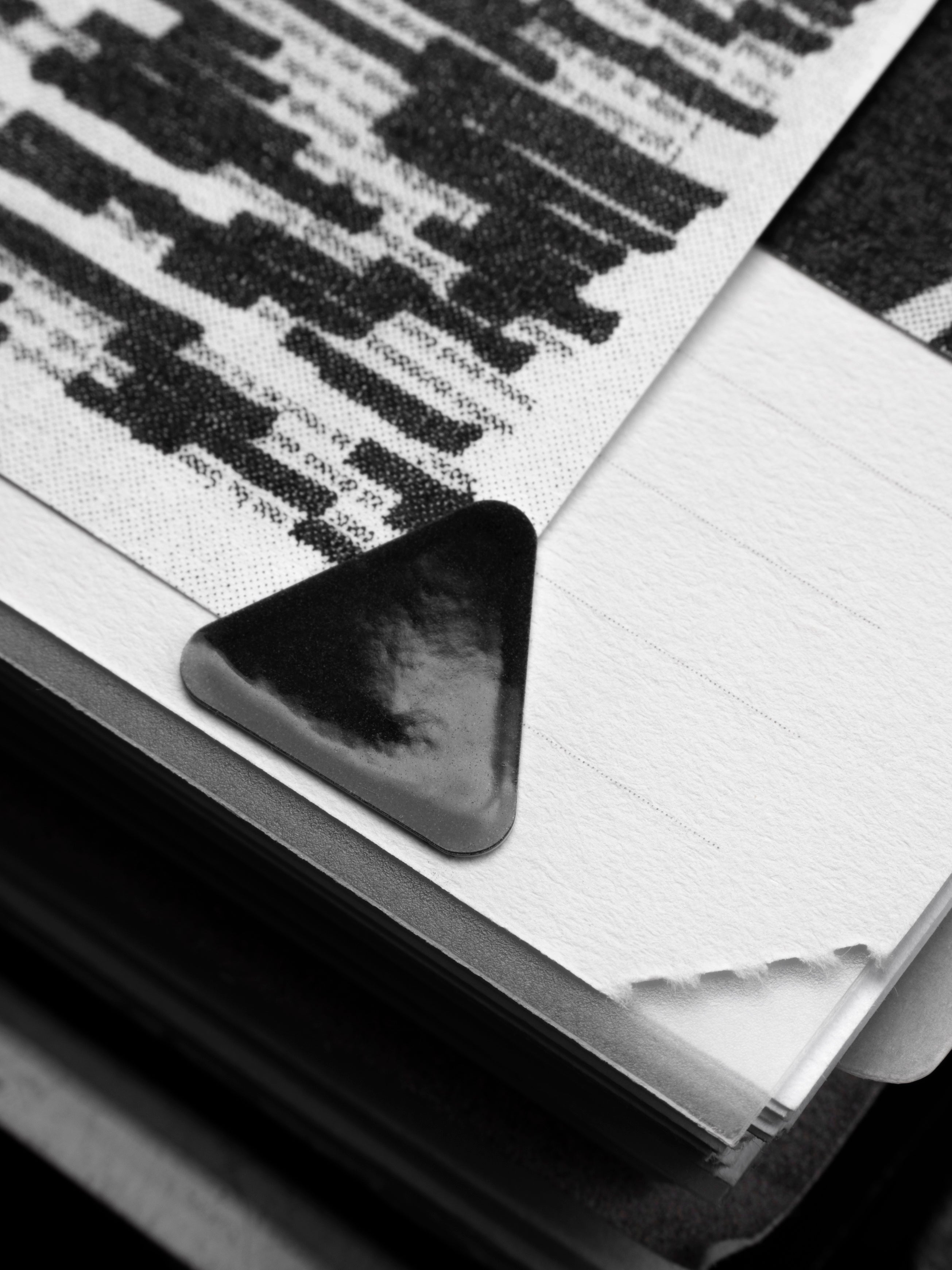 Close up of a high gloss, black triangle sticker affixing a sheet in a planner