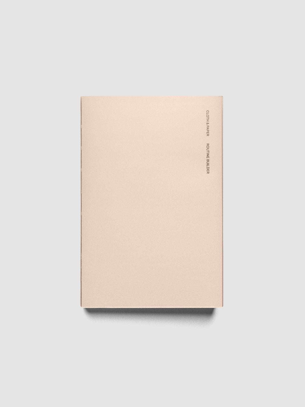 Perfect Bound Notebook | CP Petite | Routine Builder shown closed on a neutral background, plain blush cover