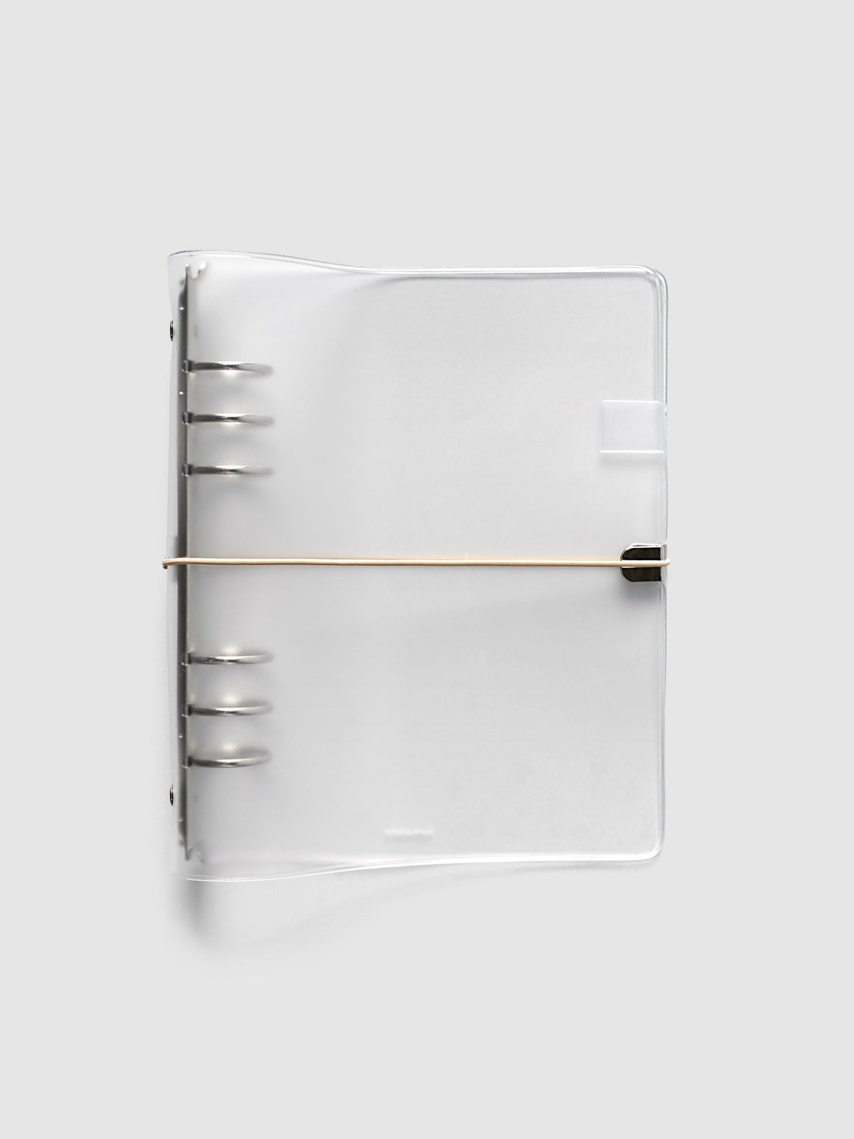 Ring Cover in frosted vinyl, A5 6-Ring Punch, closed, with the silver six-ring mechanism at the spine and a beige bungee cord hooked to a silver metal clip