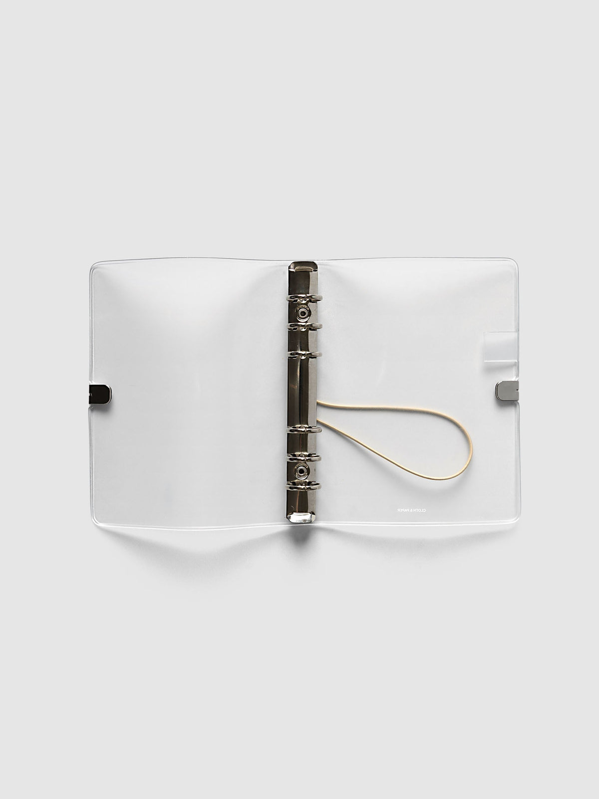Ring Cover in frosted vinyl, Personal 6-Ring Punch, open flat showing the silver six-ring mechanism, the beige bungee cord and the printed logo