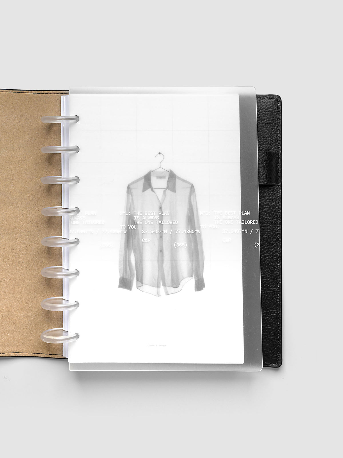 Transparent planner cover set with white printed text design and accompanying black and white dashboard with an image of a tailored shirt on a hanger. Shown discbound in a black leather folio in size Half Letter.