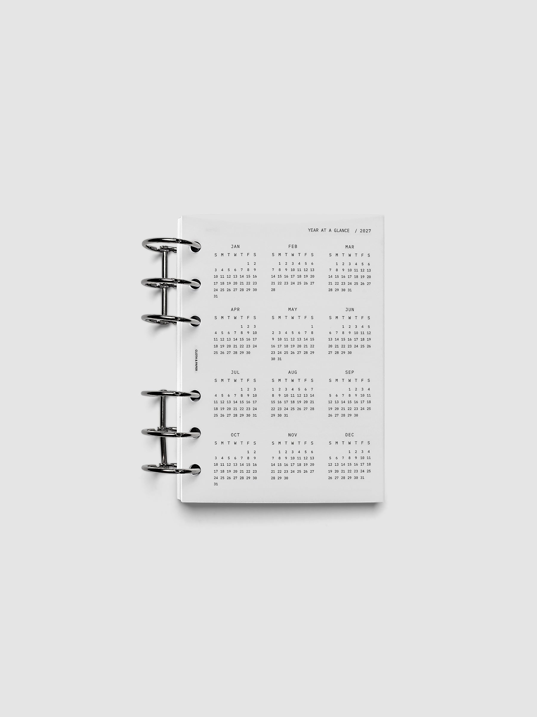 2027 Year At A Glance Dashboard Sunday Start, A6 6-Ring Punch, translucent vellum year-at-a-glance calendar shown inside a planner