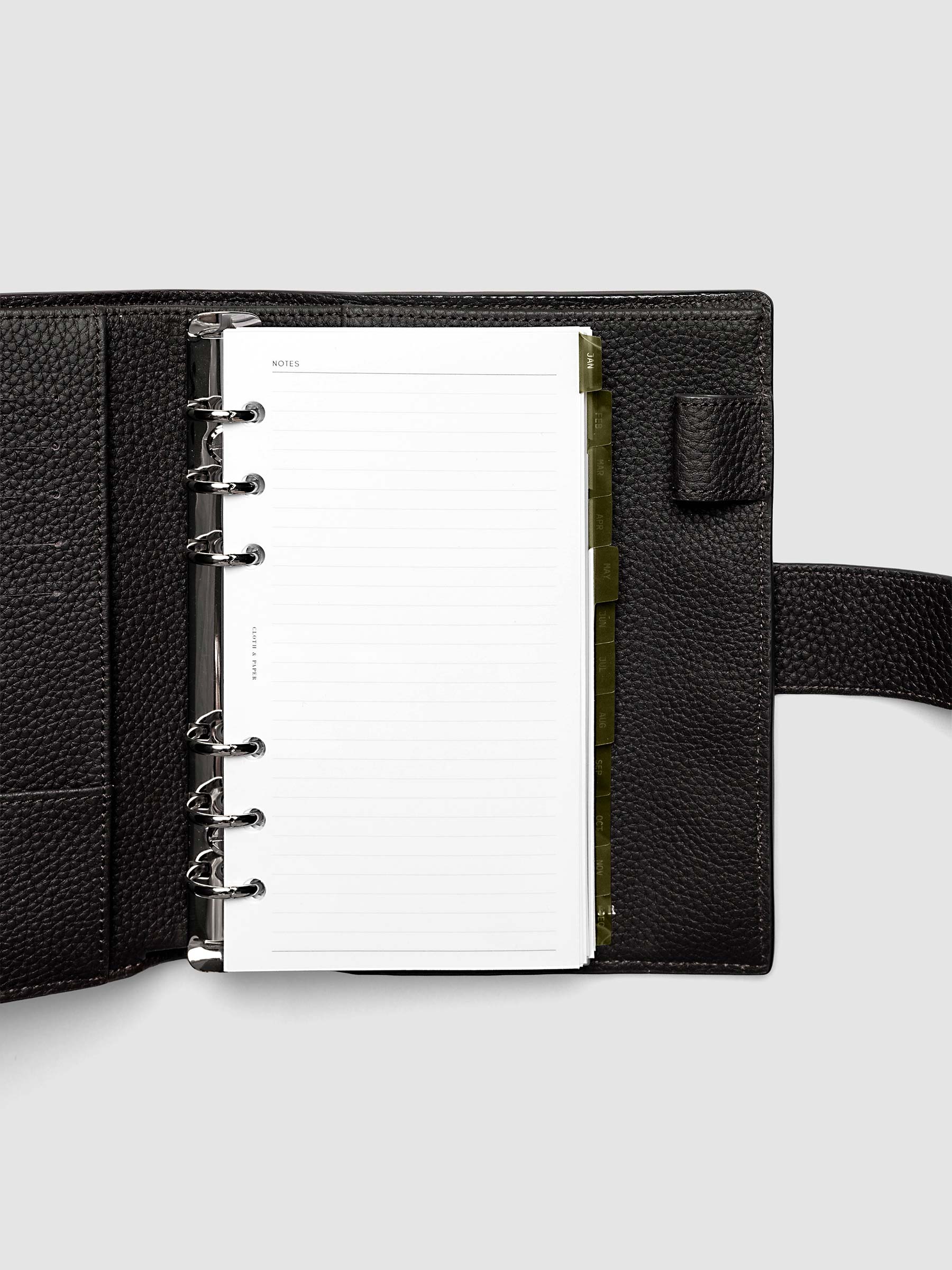 Personal 6-Ring Punch Ultra-Thin Monthly Dividers in olive green shown tabbed inside a planner