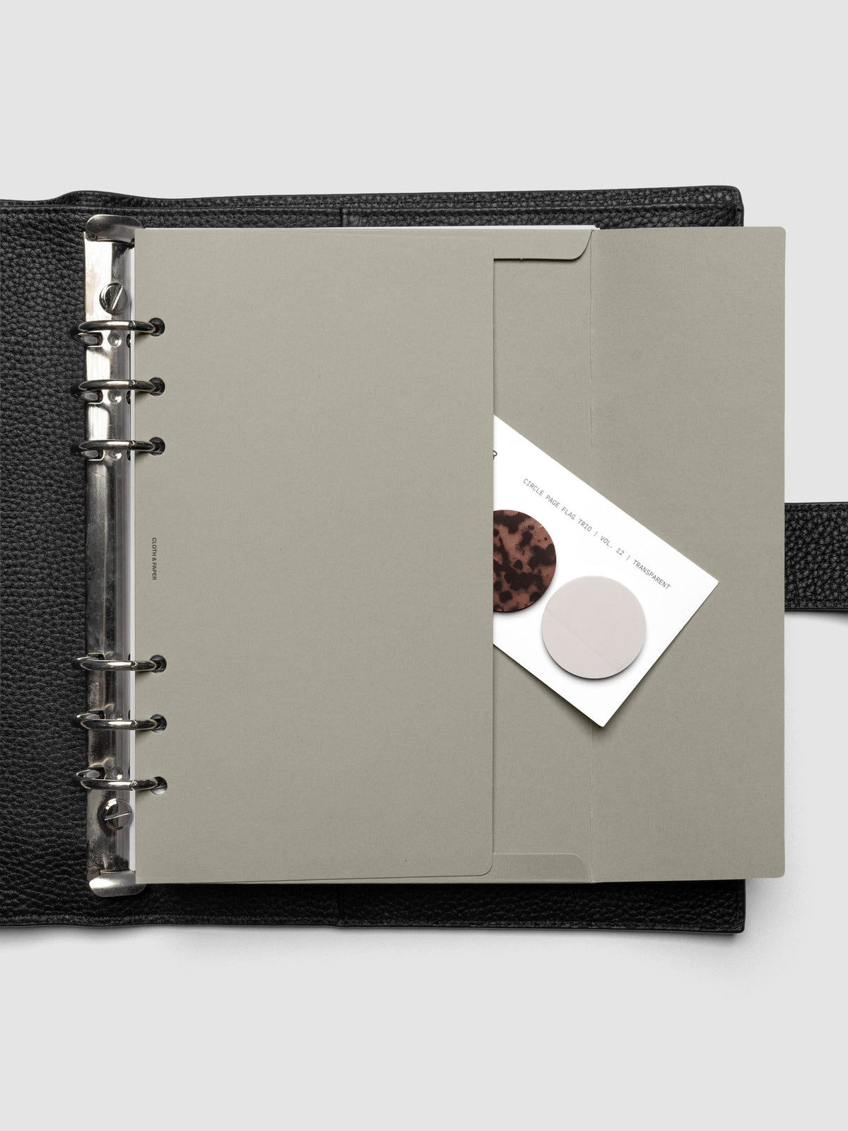 Beige Envelope Storage Holder shown inside a black, leather A5 agenda with page flags inside.