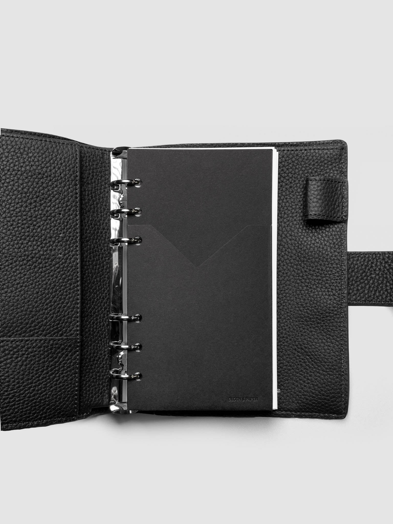Black planner paper pocket folder shown inside a planner in size Personal 6-Ring Punch
