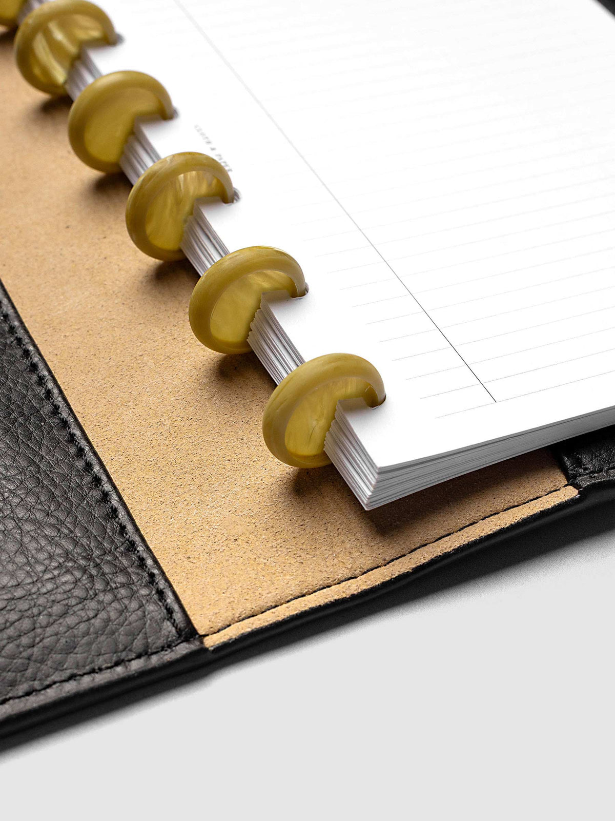 Close-up of Carrara Verde 0.75" planner discs in a discbound planner, highlighting the marbled green finish and disc construction