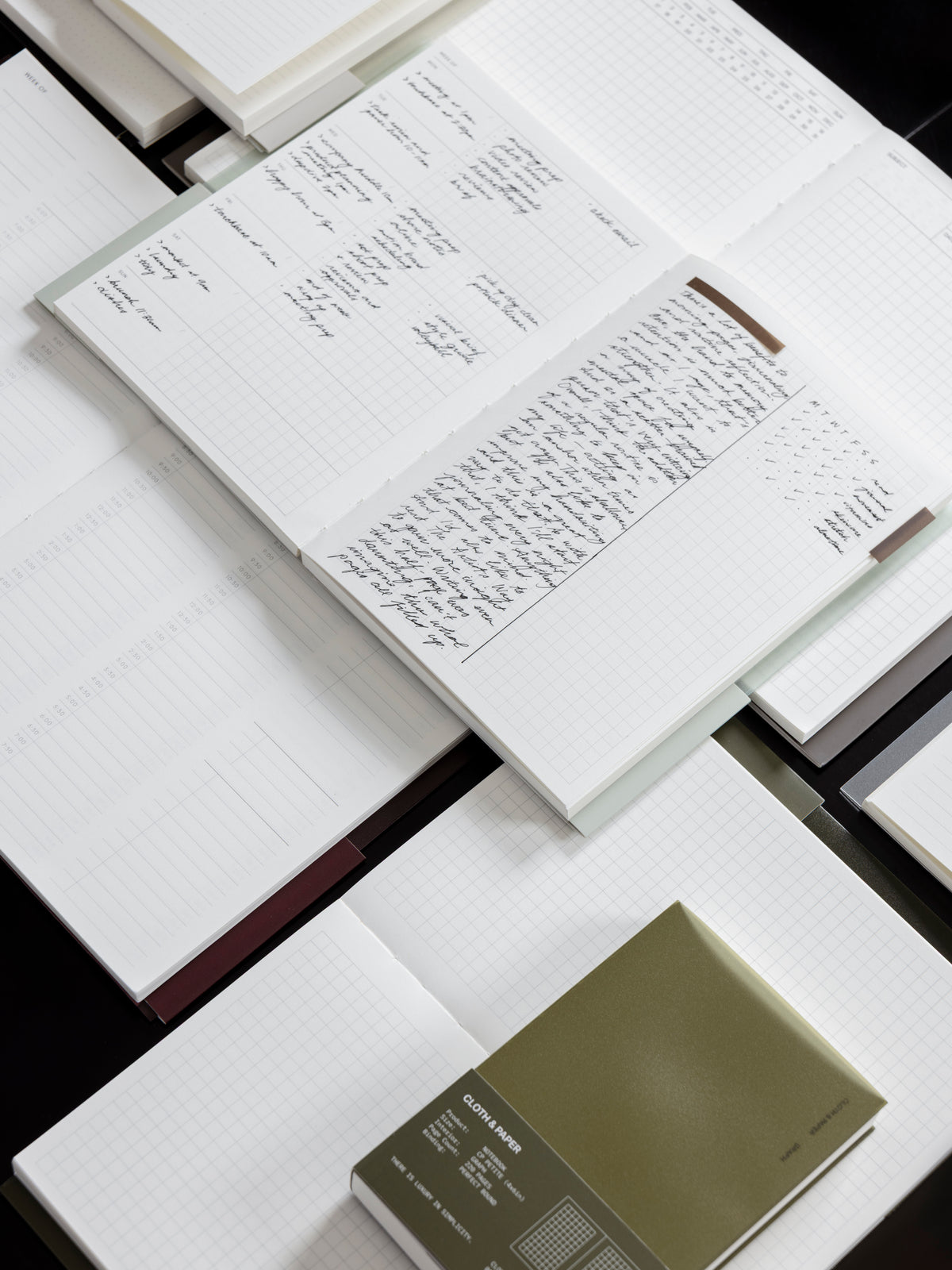 Collection of open Cloth & Paper Perfect Bound Notebooks stacked on top of each other with handwritten notes inside.