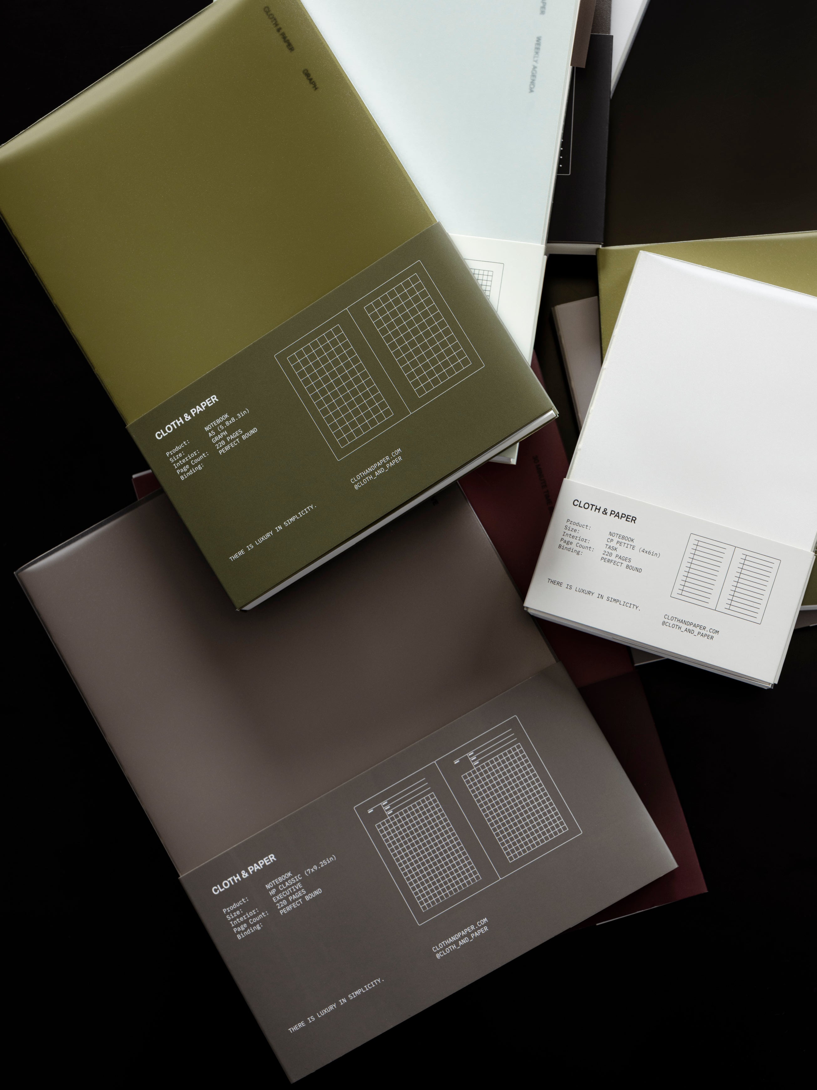 Cloth & Paper Perfect Bound Notebooks shown in various sizes, stacked, in packaging on a dark background.
