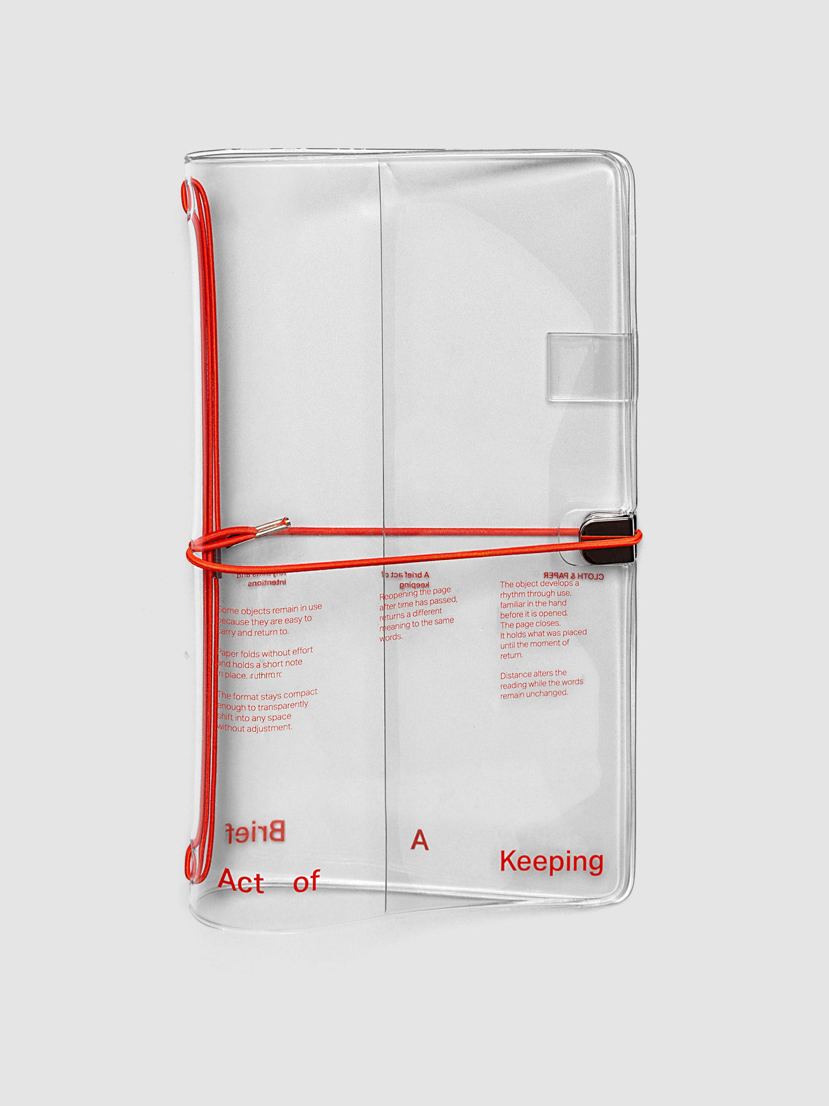 Act of Keeping Travel Notebook Cover in A5 Slim size, closed, in clear vinyl with deep orange typographic print and metal tab closure