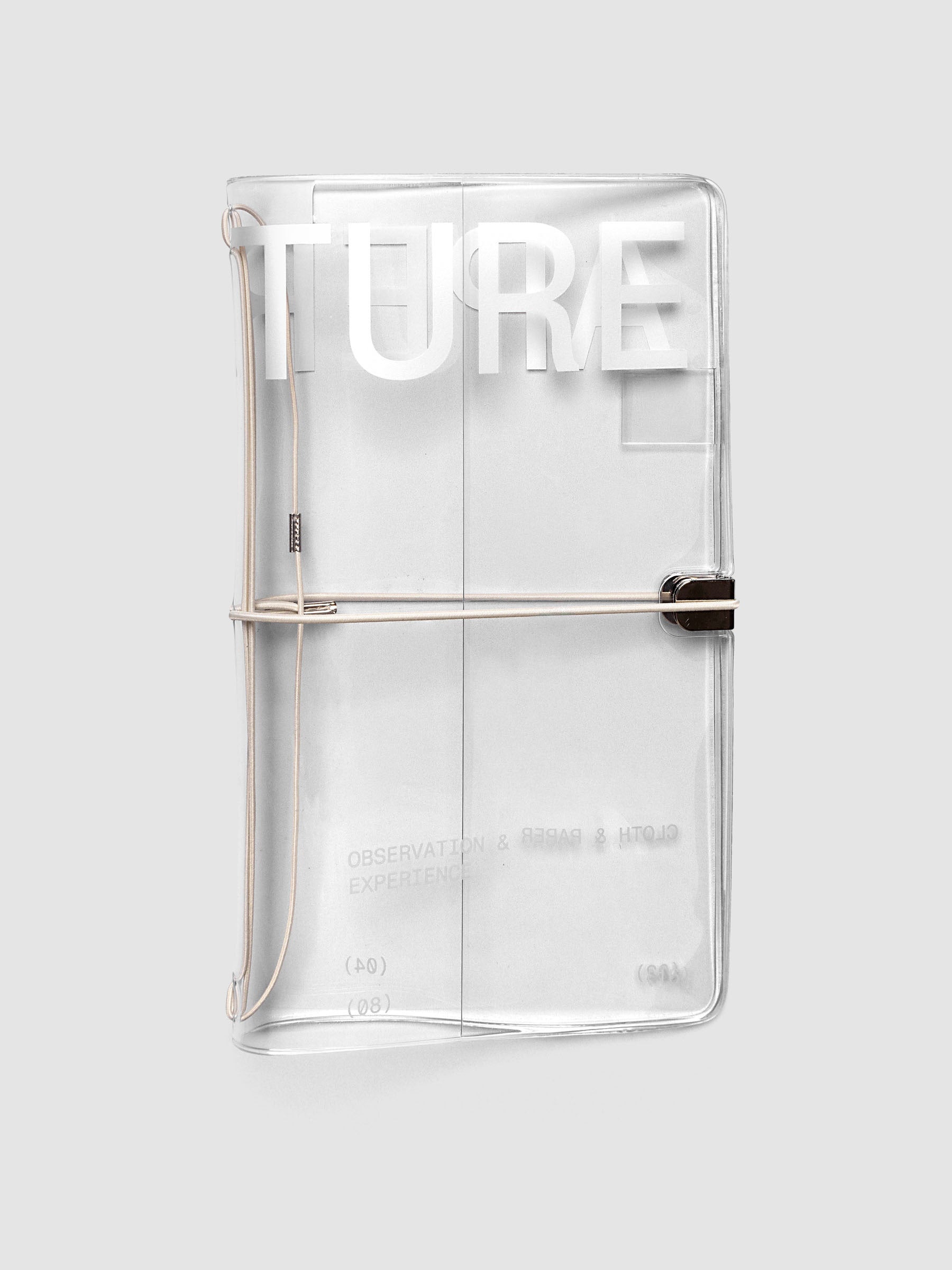 Aperture Travel Notebook Cover in A5 Slim size, closed, in clear vinyl with silver typographic print and metal tab closure