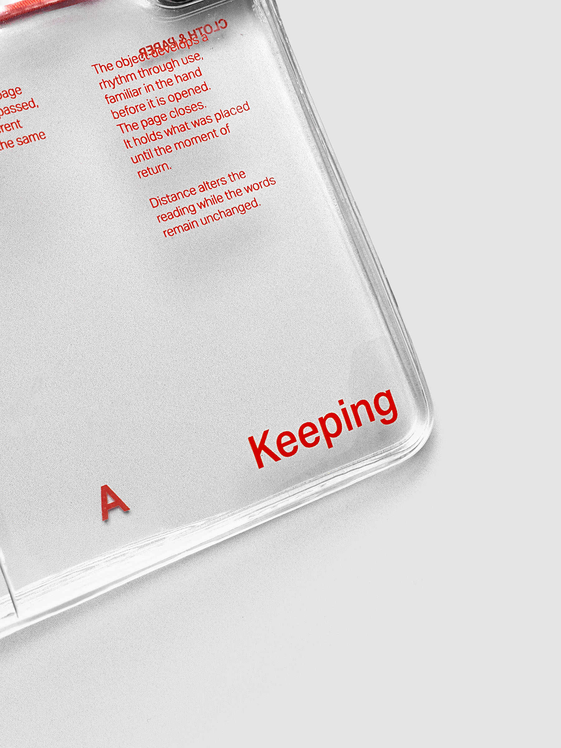 Close-up of the bottom right corner of the Act of Keeping Travel Notebook Cover in Pocket Plus size, closed, showing metal tab closure and deep orange text