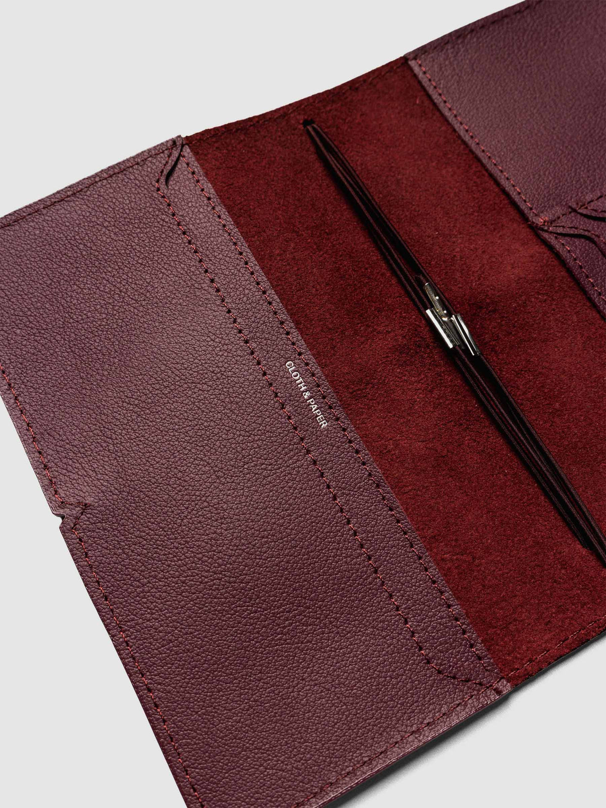 Deep red leather travel notebook cover in size Pocket Plus shown open with interior pockes and elastic bands.