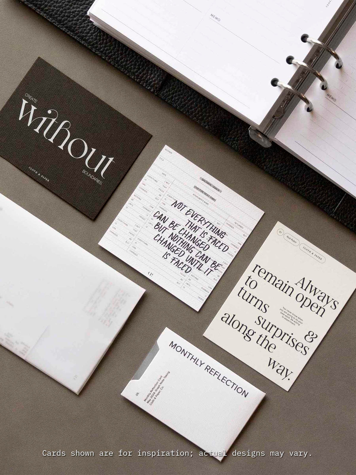 A flat lay of Cloth & Paper’s Assorted Journaling Card Set displayed next to an open planner, featuring neutral-toned cards with motivational quotes and minimalist typography, including cards labeled ‘Monthly Reflection’ and ‘Create without boundaries’.