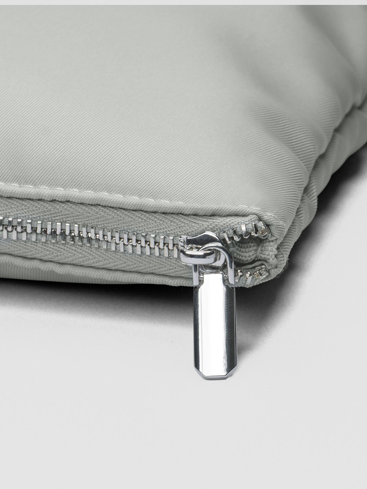 Close up of the silver zippered closure shown zipped shut on the Carried Well bag.