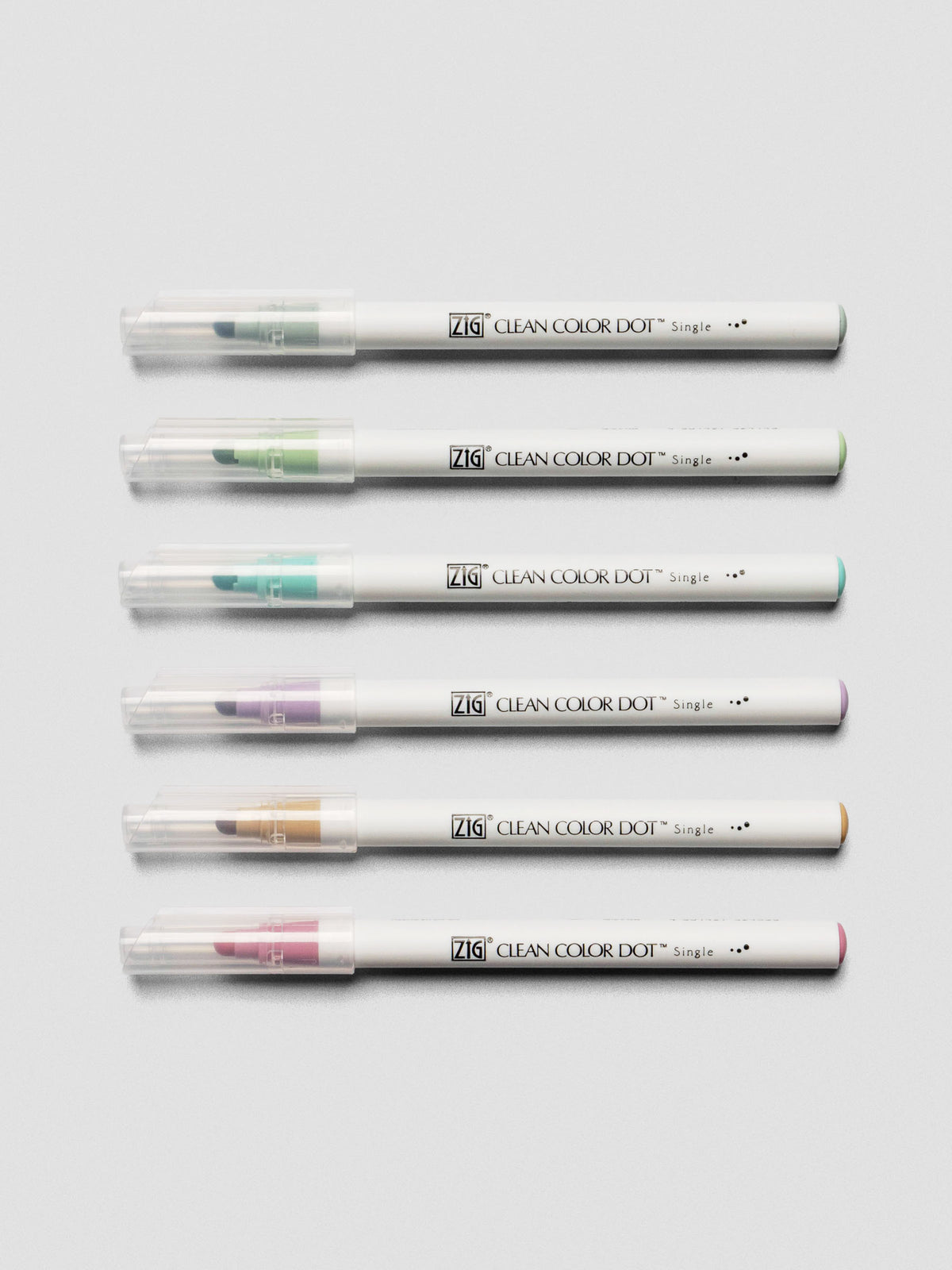 The six Kuretake ZIG Clean Color Dot Markers laid horizontally with caps on, showing the brush tips and color ends.