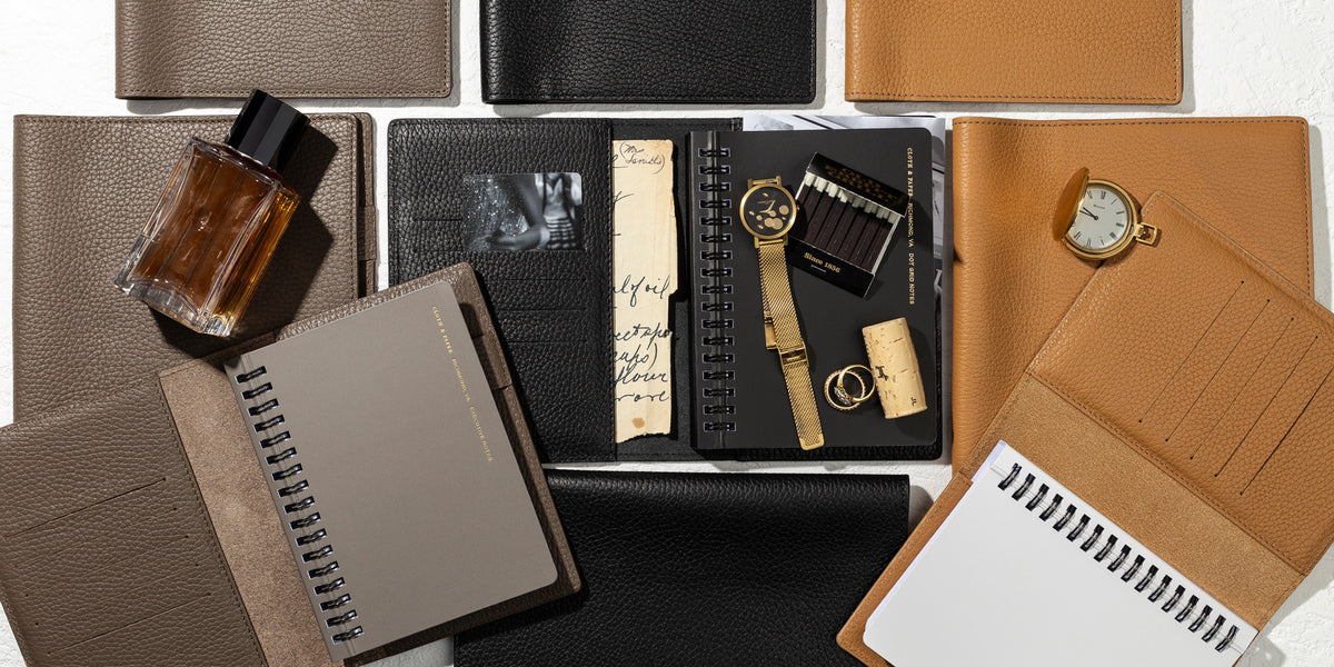 Several Heirloom Leather Folios are opened. Inside the folios are our España Notebooks. There are other personal accessories present.