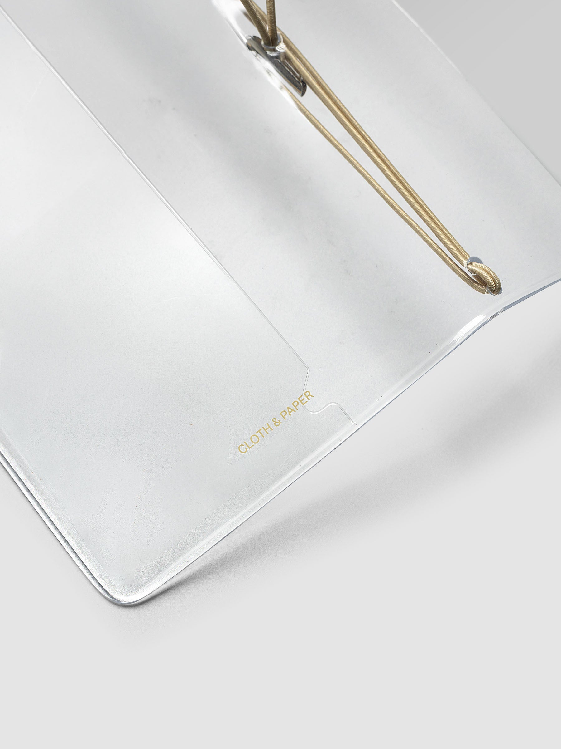 Close-up of the Clear Vinyl Travel Notebook Cover in Pocket Plus at an angle, showing the edge and bungee string.