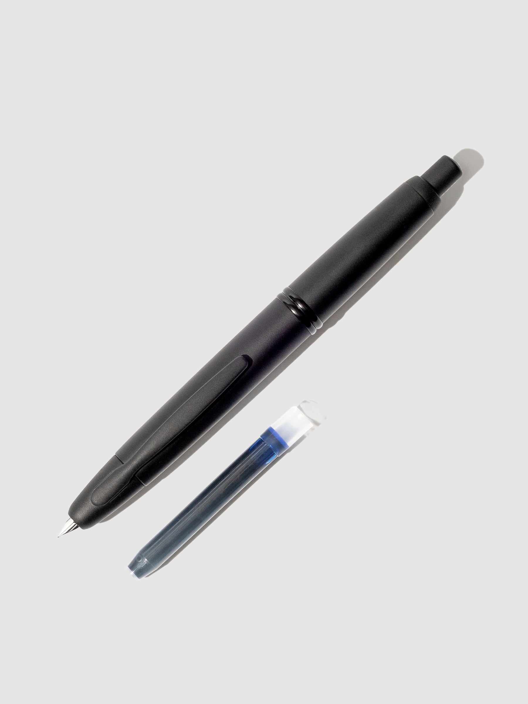 Pilot Vanishing Point fountain pen displayed next to a blue black ink cartridge on a neutral background.