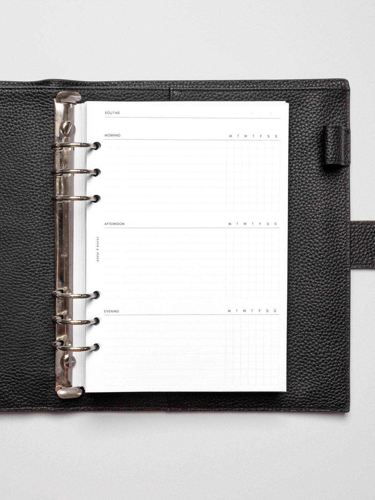 Insert in use inside a black discbound planner agenda system. Spread displays two days' worth of morning, afternoon, and evening routines.