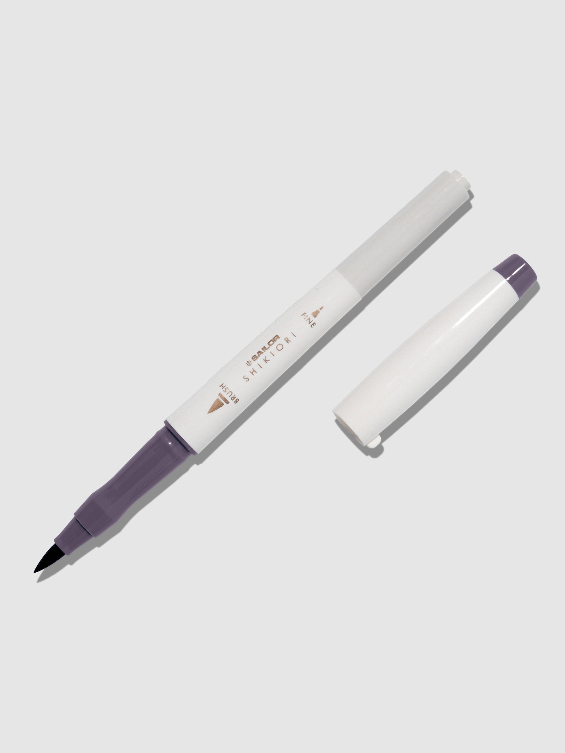 Brush pen displayed on a neutral background. It is uncapped with its brush nib exposed, and the cap lying parallel to the marker. Color pictured is Chushu.