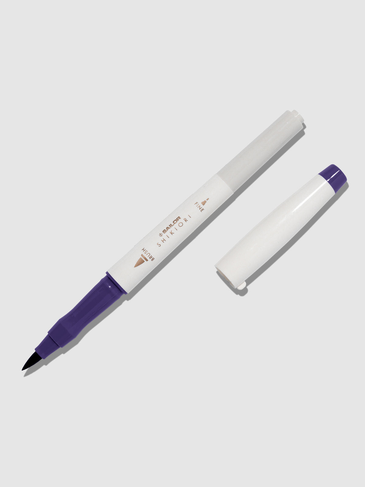 Brush pen displayed on a neutral background. It is uncapped with its brush nib exposed, and the cap lying parallel to the marker. Color pictured is Shigure.