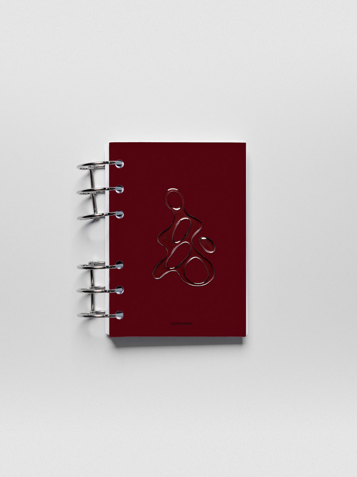 Dark red, semi-transparent, and glossy plastic planner dashboard with organic raised shape design in size A6 shown ringbound.