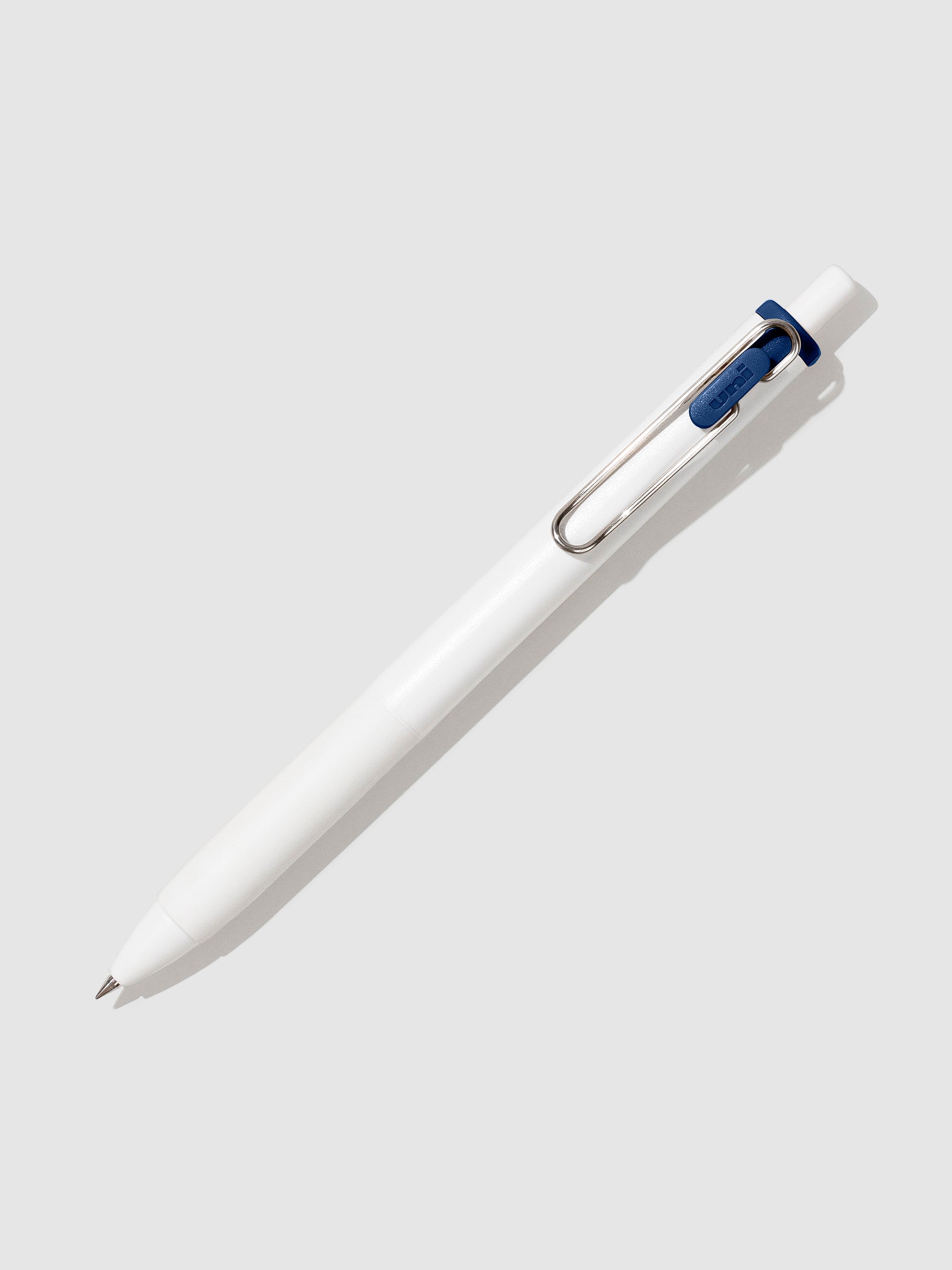 Uni-ball One Gel Pen, Blue Black, Cloth and Paper. Pen tilted slightly to the right on a neutral background.