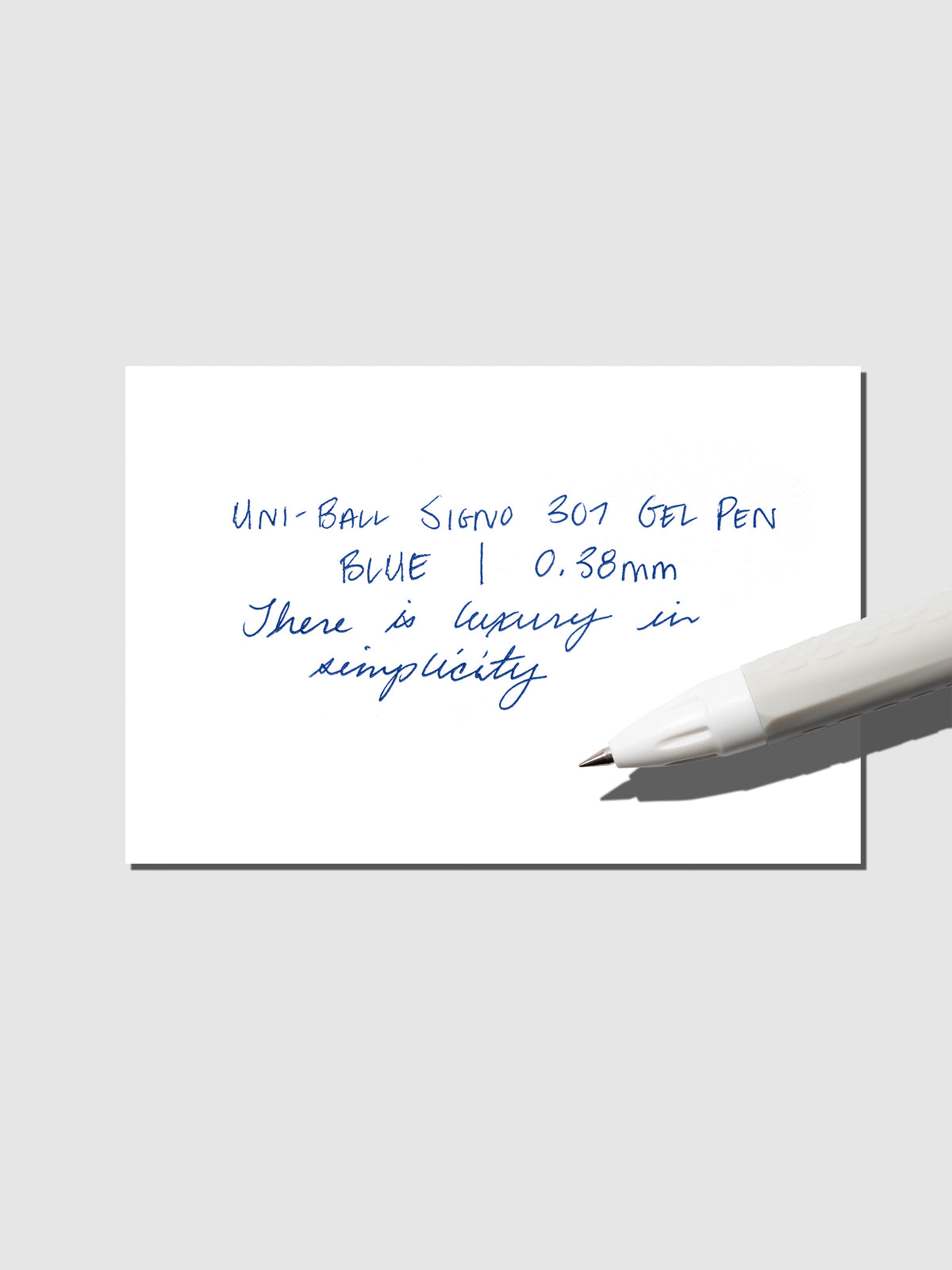 Uni-Ball Signo Gel pen resting on a pen test sheet. The sheet shows the pens specs. Color pictured is Blue.