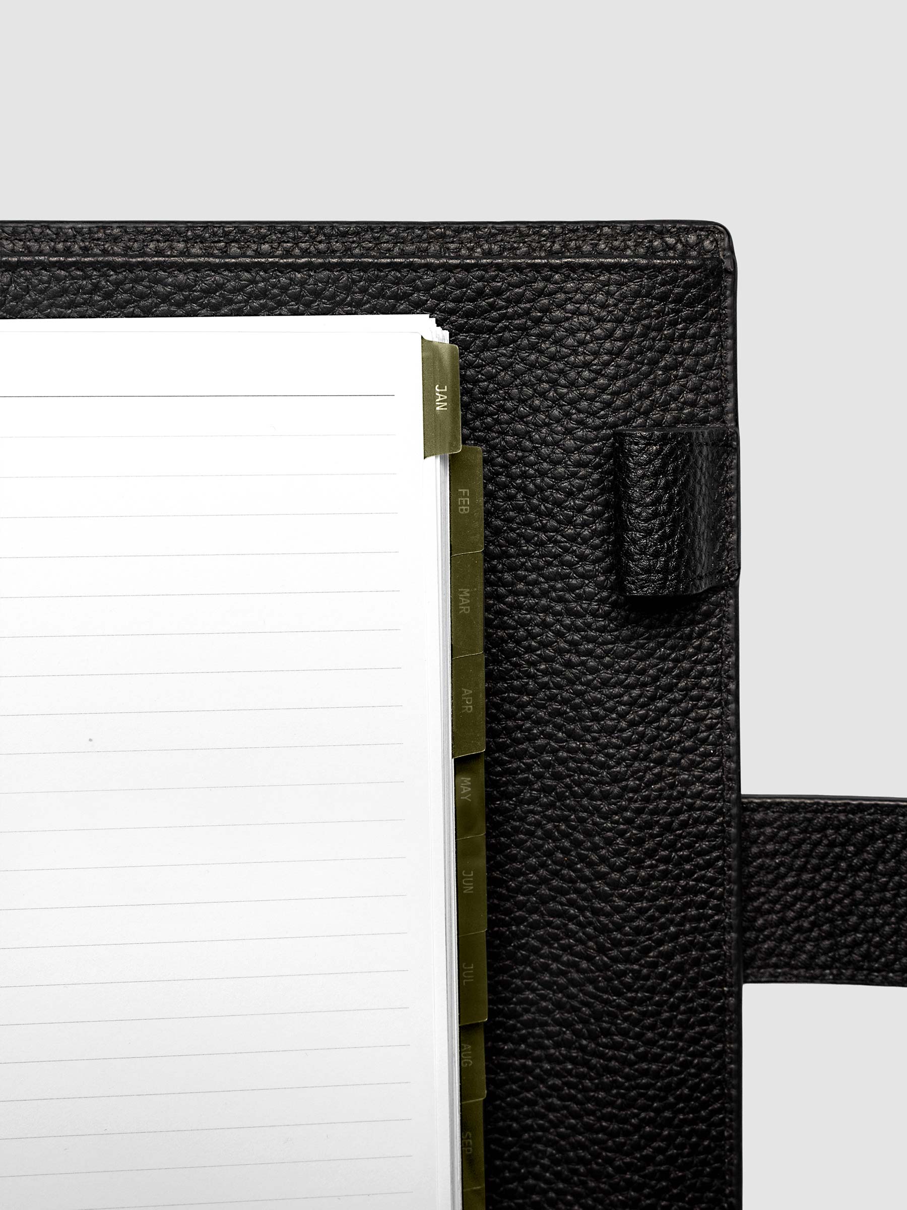 Top right corner close-up of olive green monthly divider in A5 6-Ring Punch planner showing tab label detail
