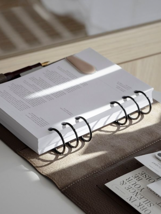 An image of an A5 6-ring planner in a leather folio, illuminated by sunlight.