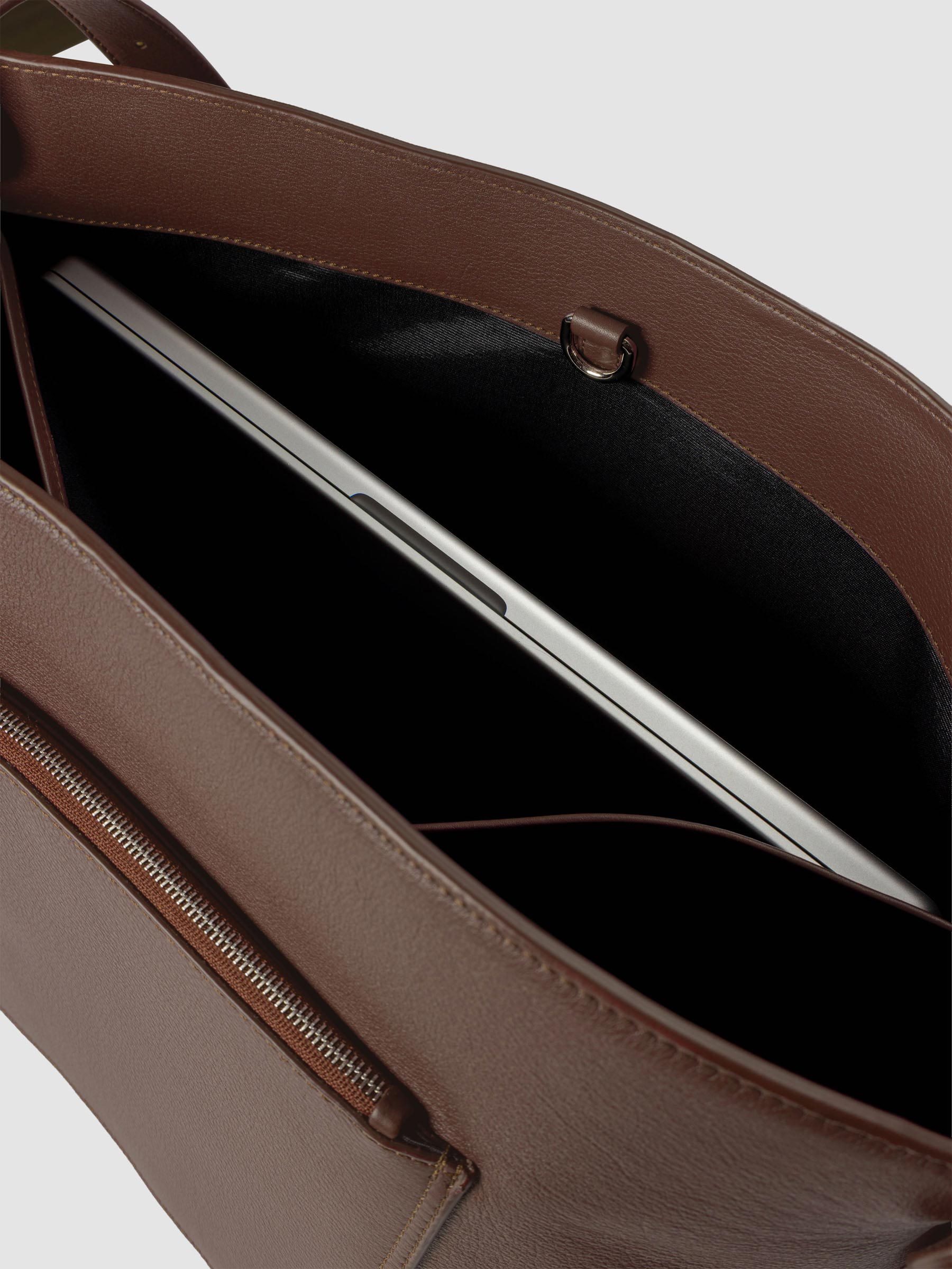Detail view of a laptop inside the inner laptop pocket of The Metro Tote in the color Cordoba.