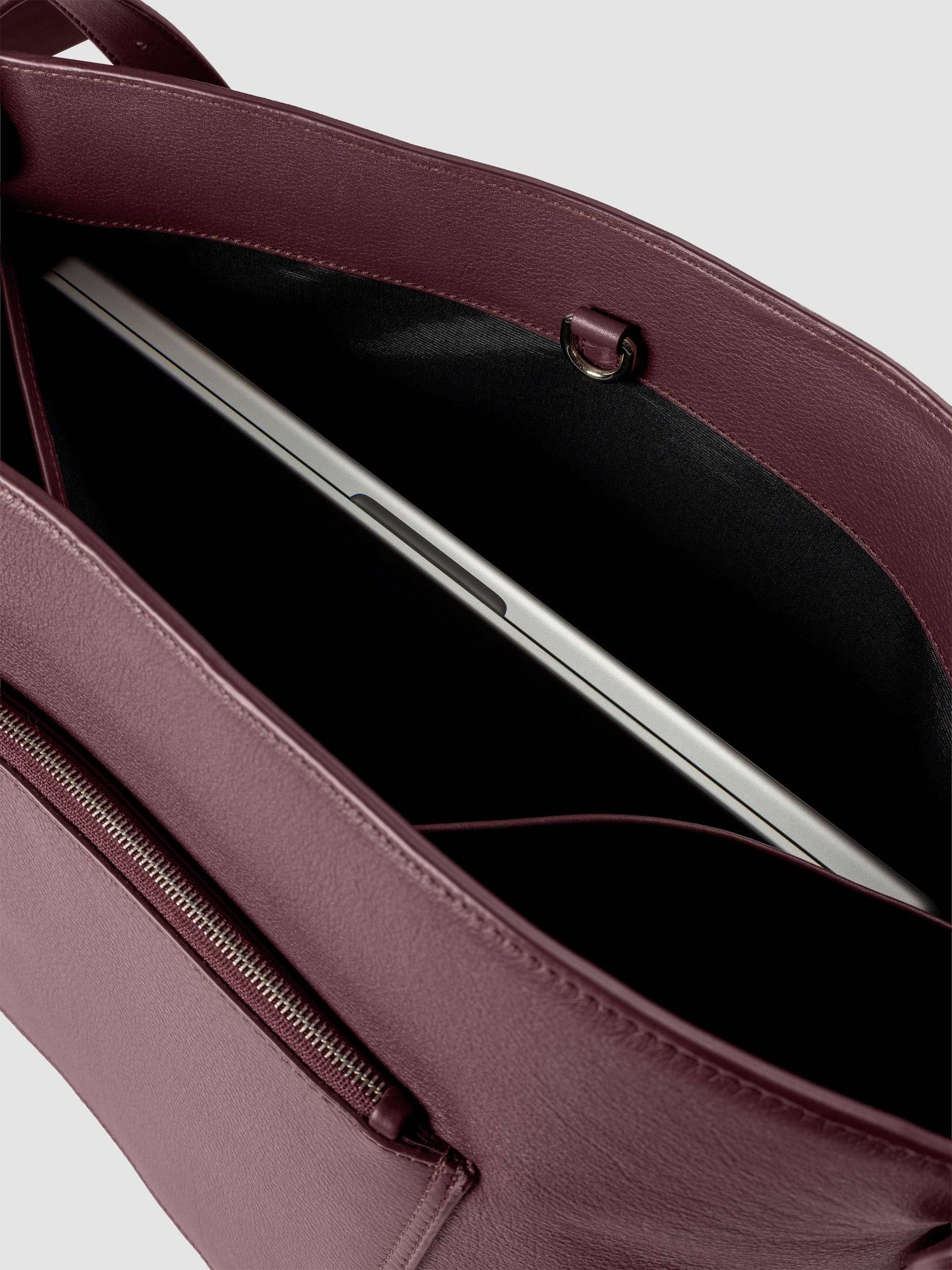 Detail view of a laptop inside the inner laptop pocket of The Metro Tote in the color Madrid.