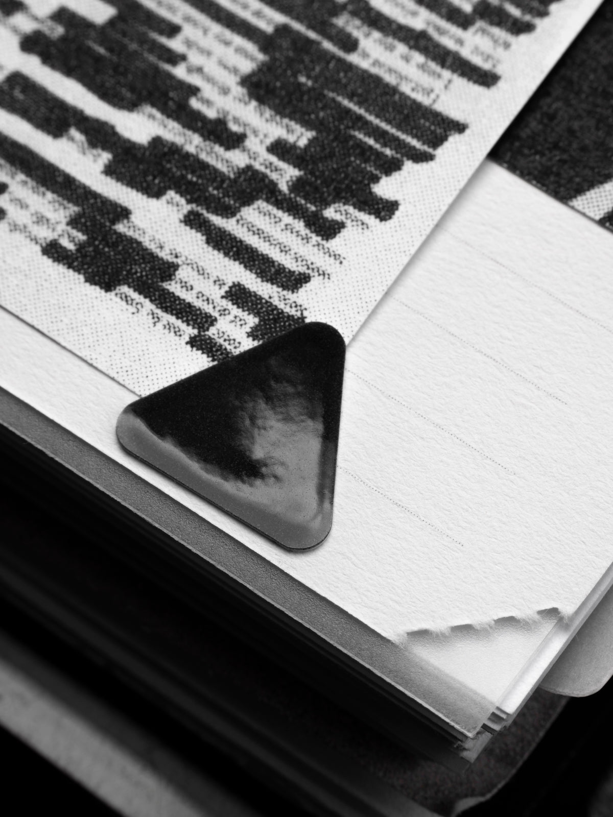 Close up of a high gloss, black triangle sticker affixing a sheet in a planner