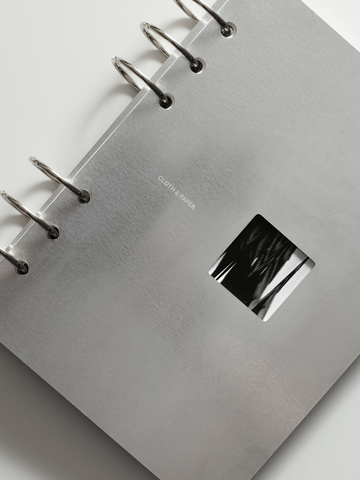 Silver ringbound notebook with a metallic cover on a light gray background