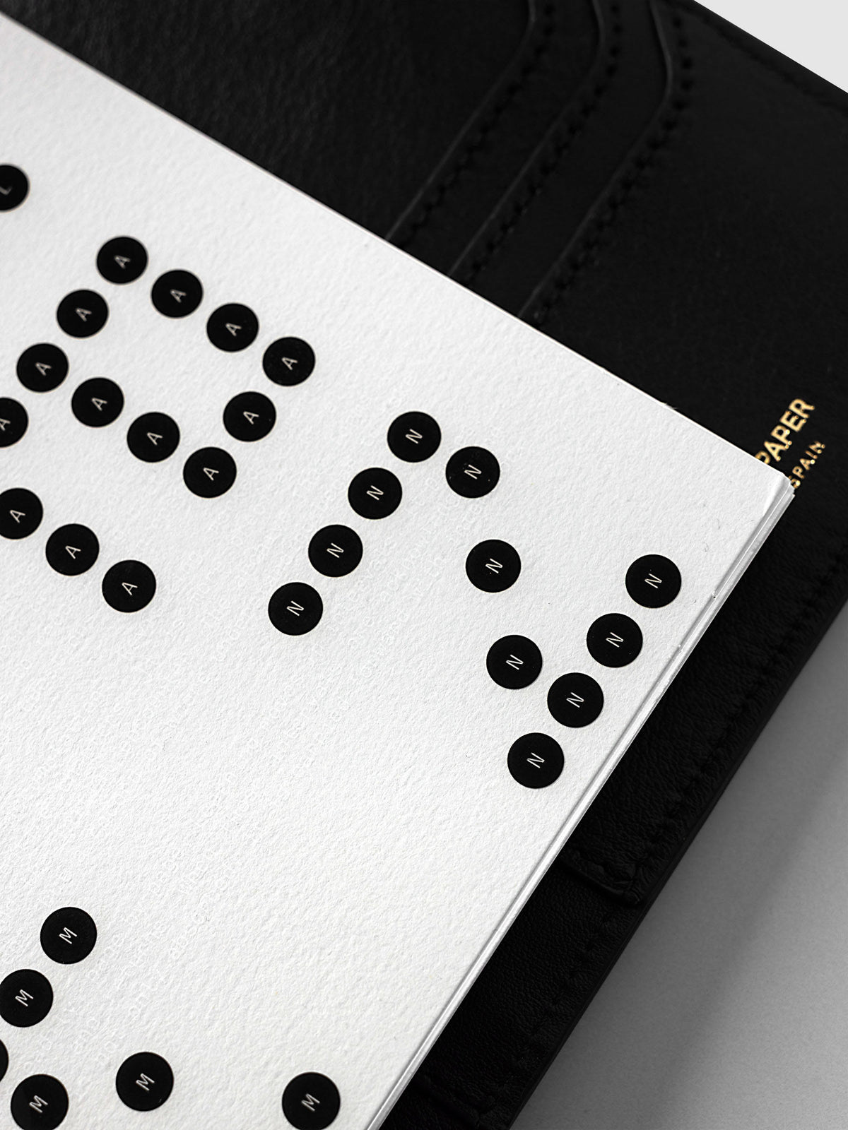 Scantron Dashboard Duo, A5 6-Ring Punch, close-up of the right edge of the pair against the black leather cover