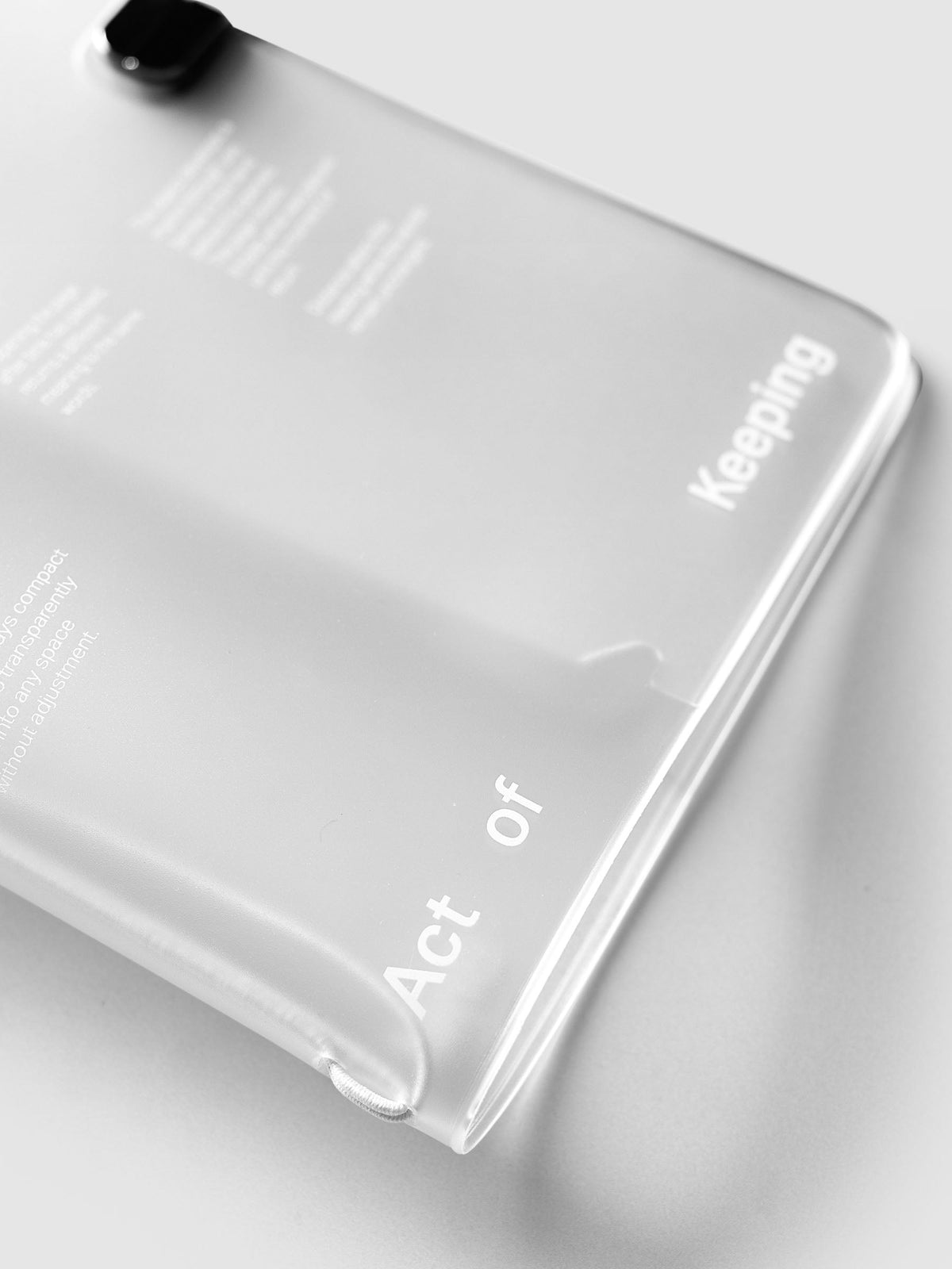Angled close-up of the white Act of Keeping lettering at the base of the frosted vinyl travel cover