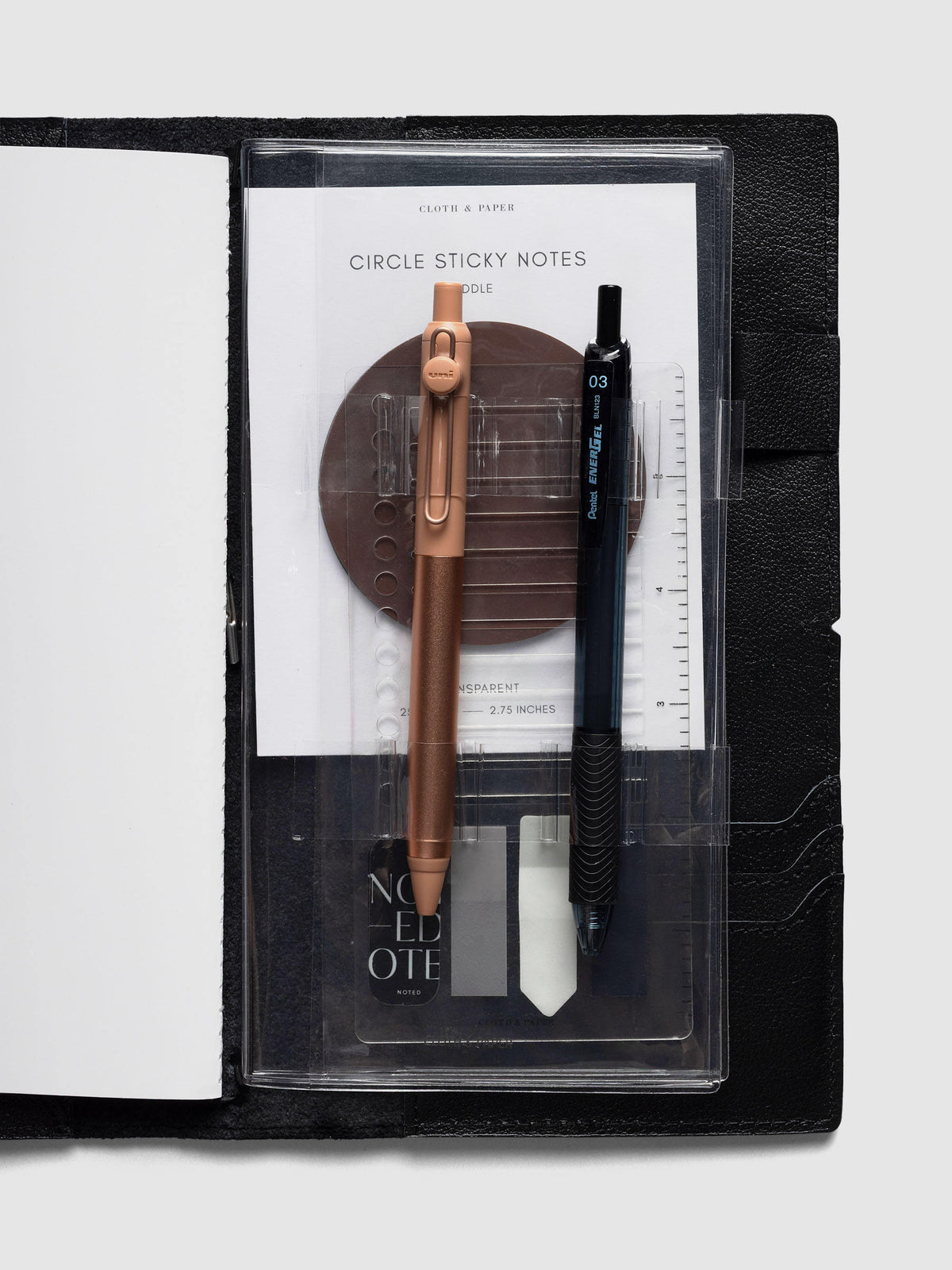 Travel Tool Kit, A5 Slim, inside a black travel notebook, holding a copper and a black gel pen over sticky notes and page flags