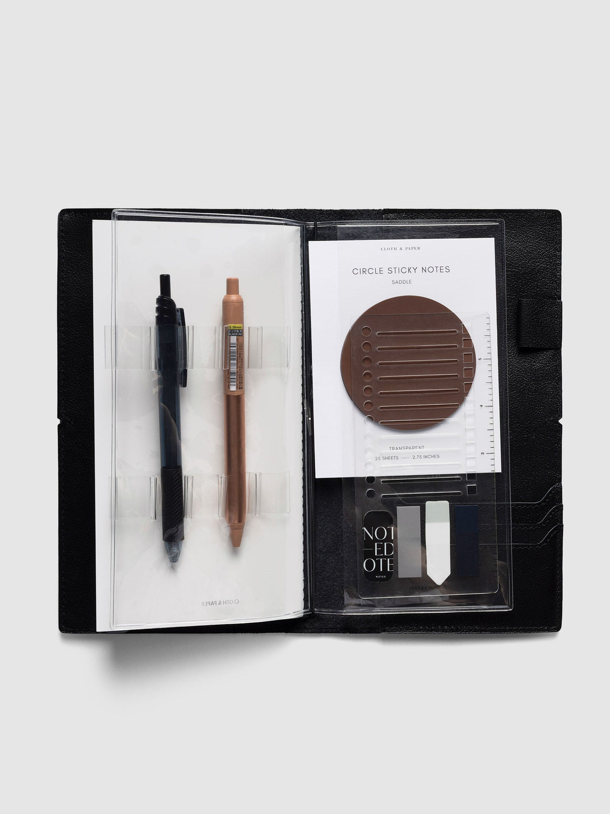 Travel Tool Kit, A5 Slim, open inside a black travel notebook, two pens in the loops beside a pocket of sticky notes and page flags