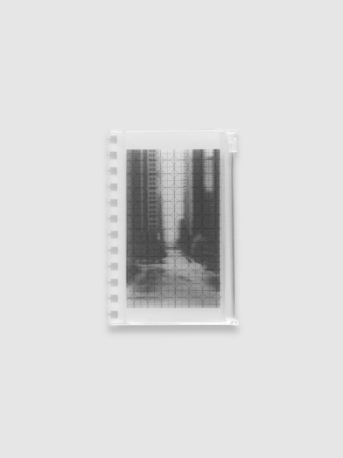 Frosted transparent zippered storage pouch pre-punched for CP Petite Spiral notebooks, holding the black and white blurred photo insert under the clear circle and graph overlay. Shown in size CP Petite Spiral.