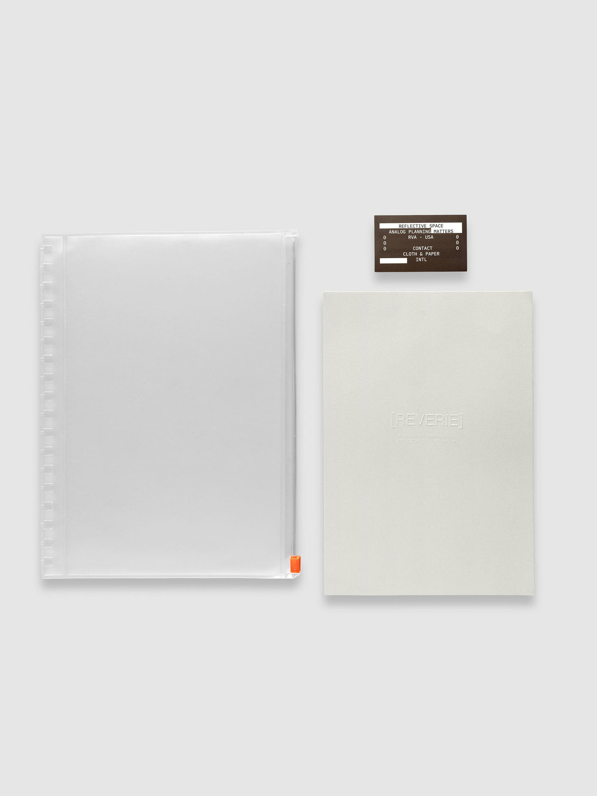 One clear zippered pouch with an orange zipper pull, one light grey embossed paper dashboard and one brown sticker laid side by side. Shown in size HP Classic Spiral.