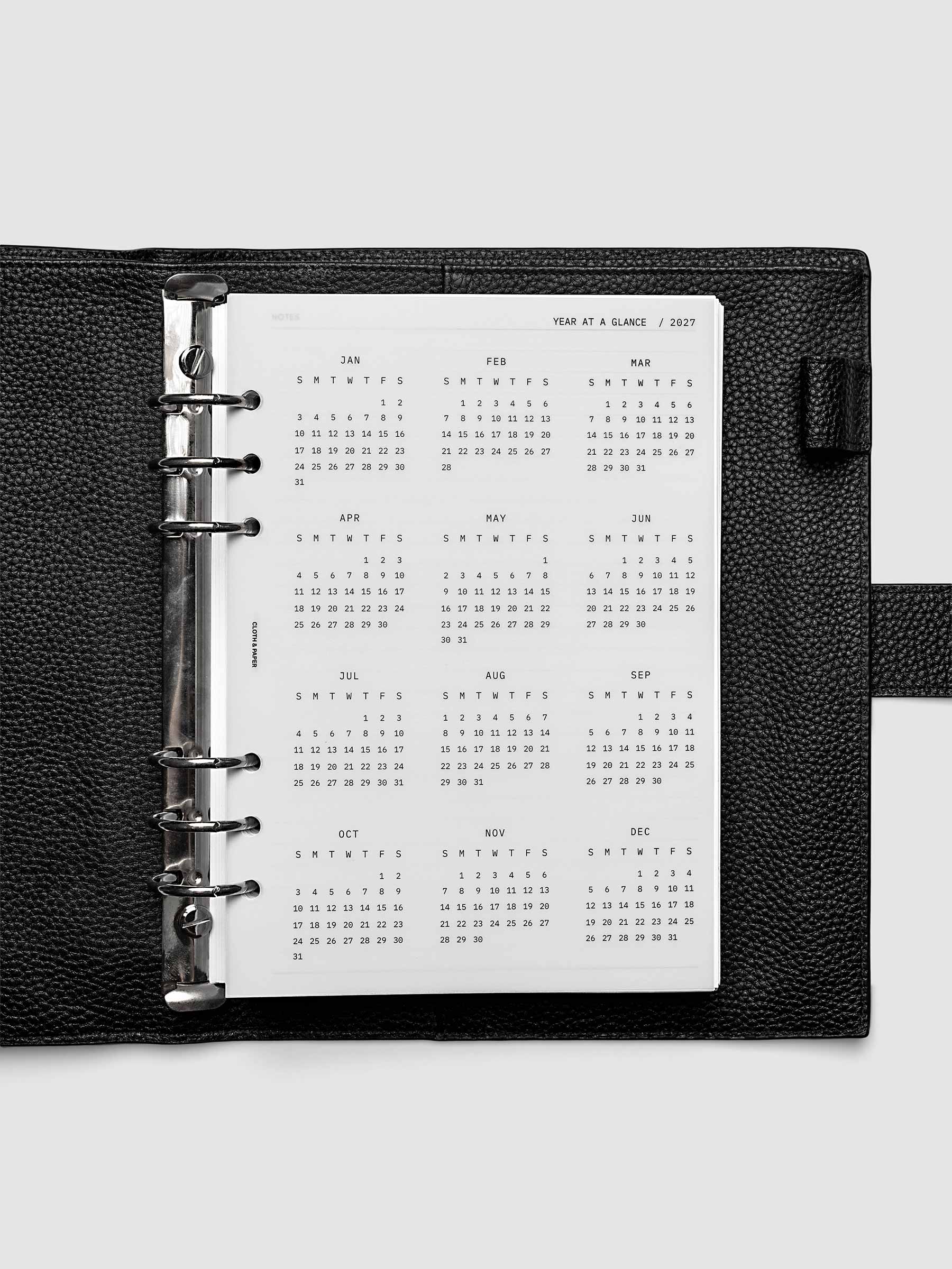 2027 Year At A Glance Dashboard Sunday Start, A5 6-Ring Punch, translucent vellum year-at-a-glance calendar shown inside a planner