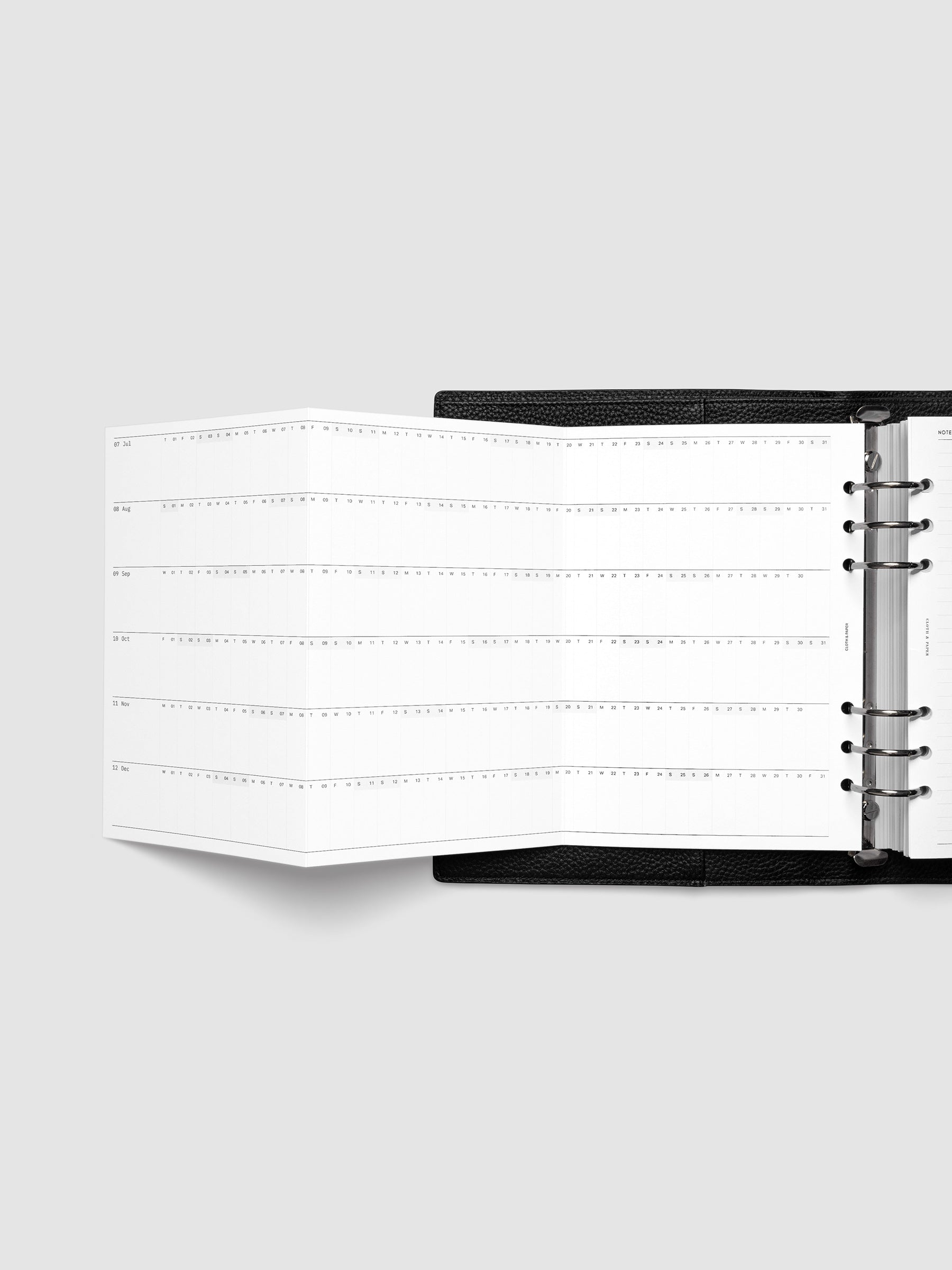 2027 Dated Fold Out Insert fully unfolded inside a A5 6-Ring Punch 6-ring planner, showing six months of dated calendar boxes across one side.