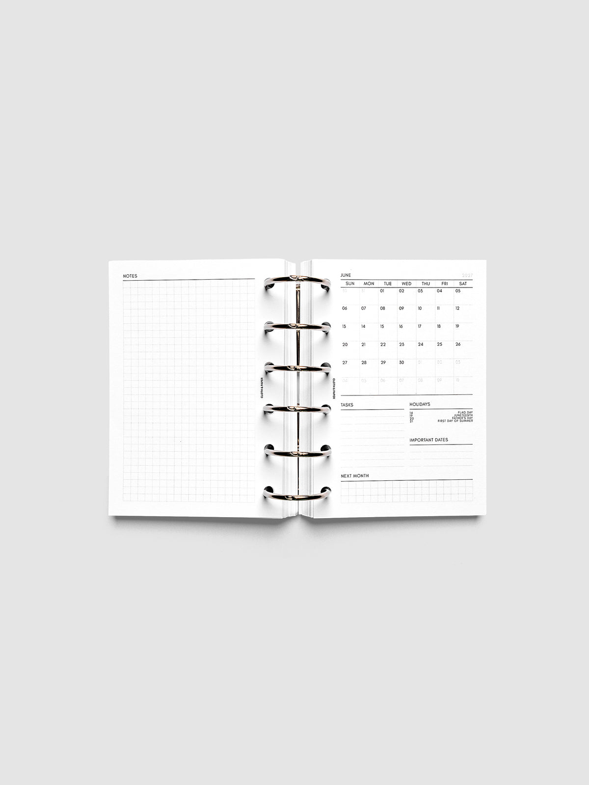 2027 Dated Monthly Admin Inserts open inside a Pocket 6-Ring Punch 6-ring planner, showing the fully open graph left page alongside the Sunday start monthly calendar, task section, holiday reference, important dates, and next month preview on the right.