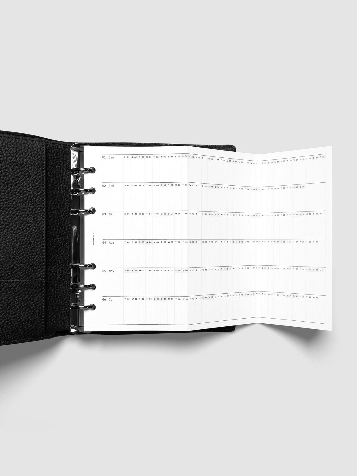 2027 Dated Fold Out Insert fully unfolded inside a Personal 6-Ring Punch 6-ring planner, showing six months of dated calendar boxes across one side.