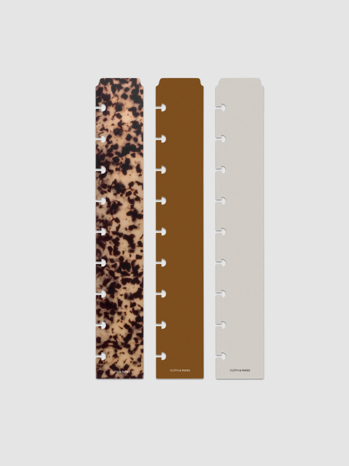 Narrow Page Marker Set Vol. 2, a set of 3 page markers for planners and notebooks shown in size HP Classic. Includes one tortoiseshell pattern, one solid brown, and one solid grey page marker.
