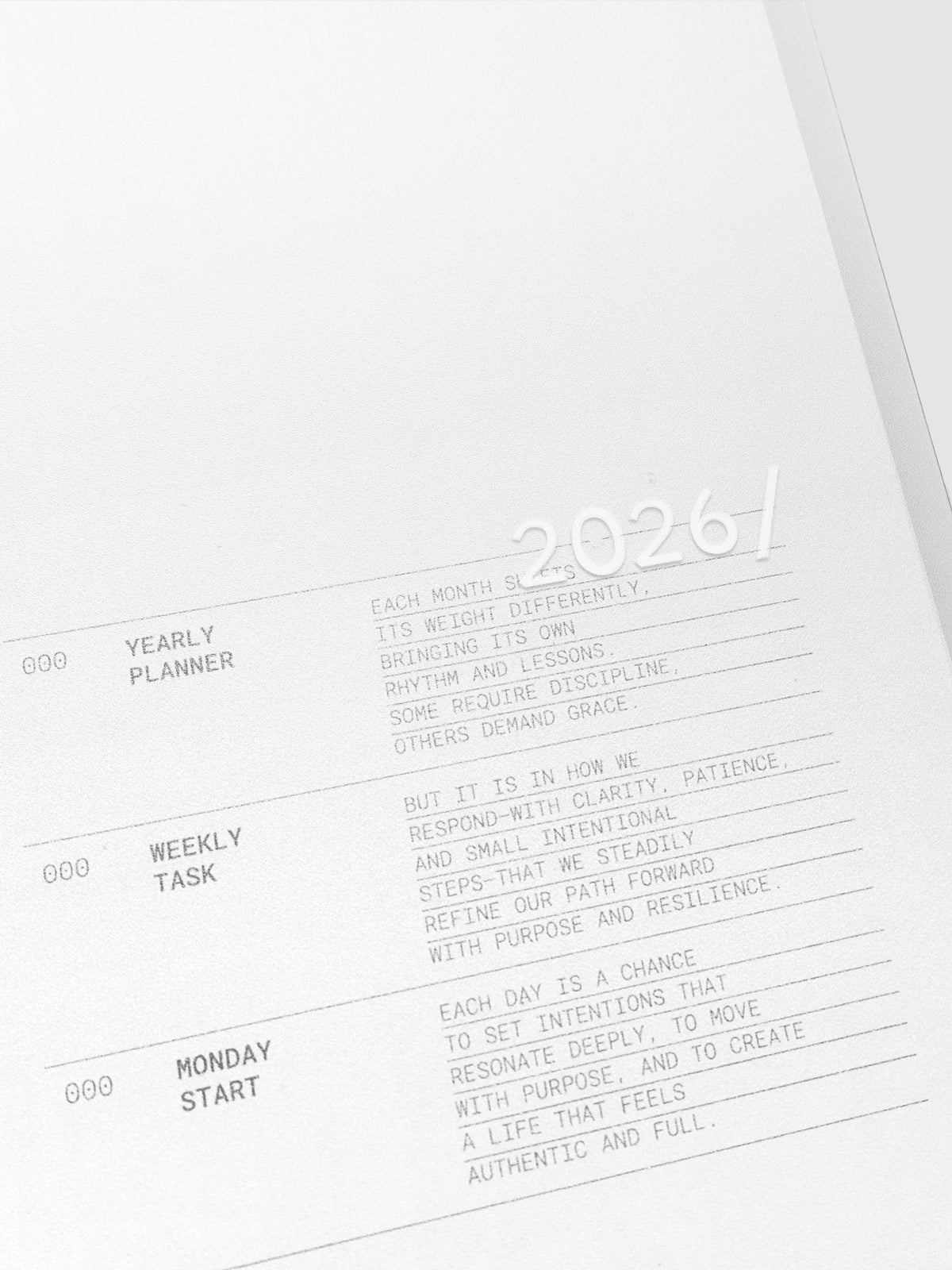 Close up of the 2026 Weekly Task Notebook cover with 2026 printed in white on the front. The transparent cover shows the page below with a description of the planner.