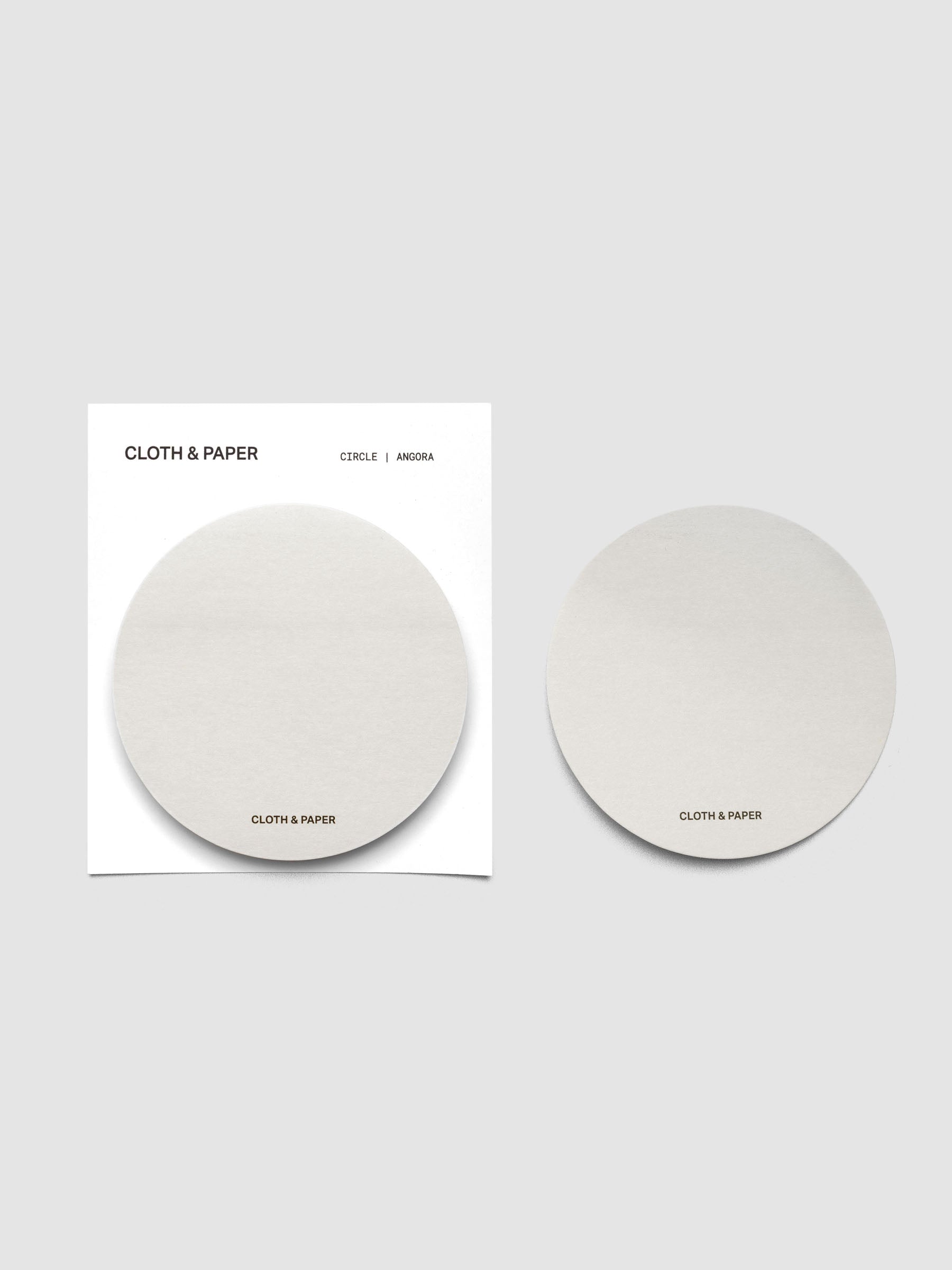 A stack of grey circular sticky notes on a white backer card with one note peeled off and placed beside it