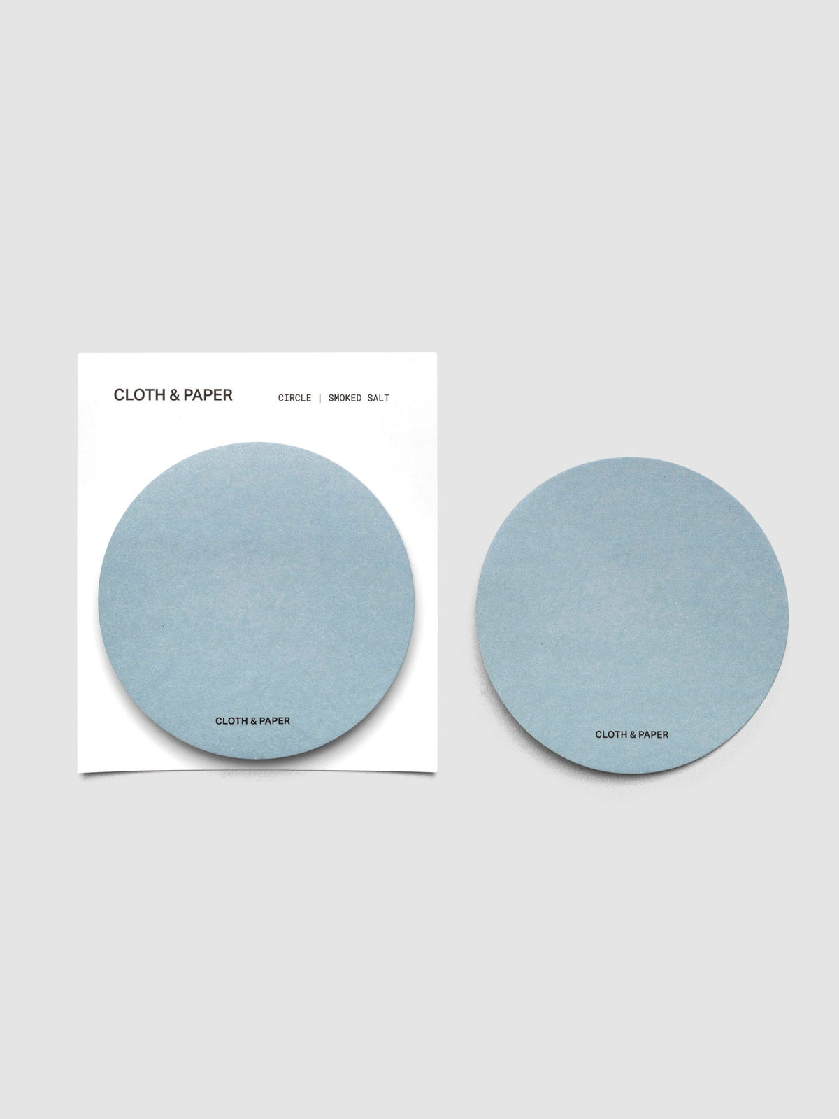 A stack of light blue circular sticky notes on a white backer card with one note peeled off and placed beside it
