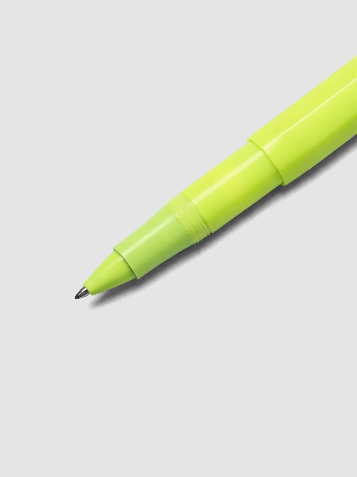 Close up view of the rollerball tip on a lime green pen.